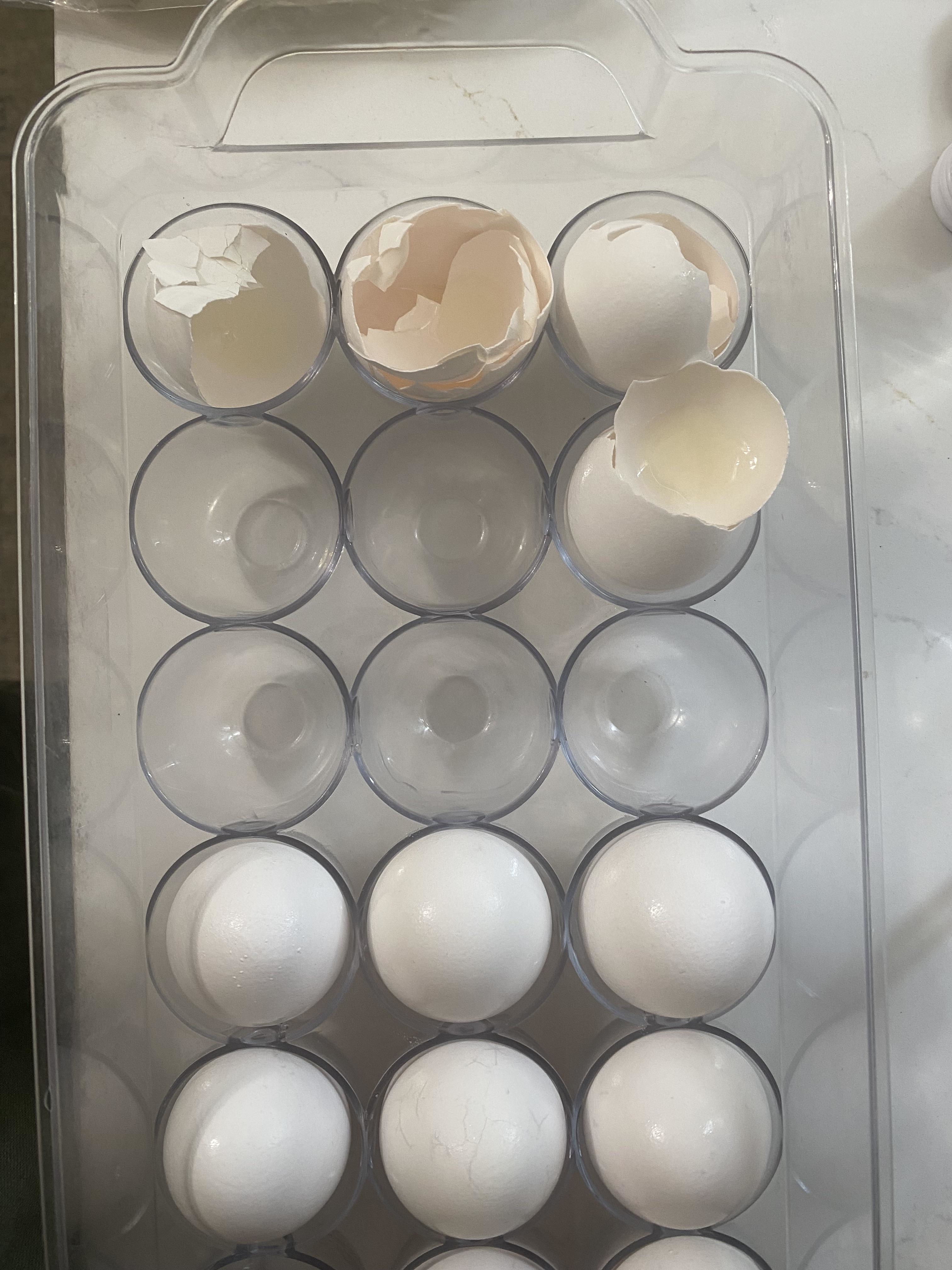 An egg carton with two cracked and four whole eggs at the top; the rest of the slots are empty