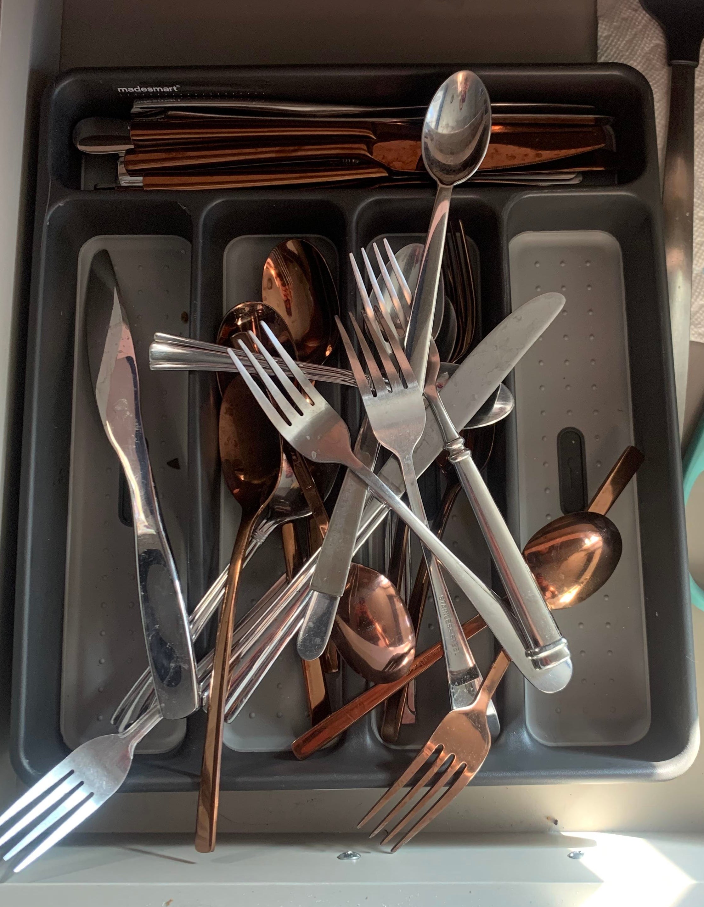 A kitchen drawer with disorganized cutlery and scissors
