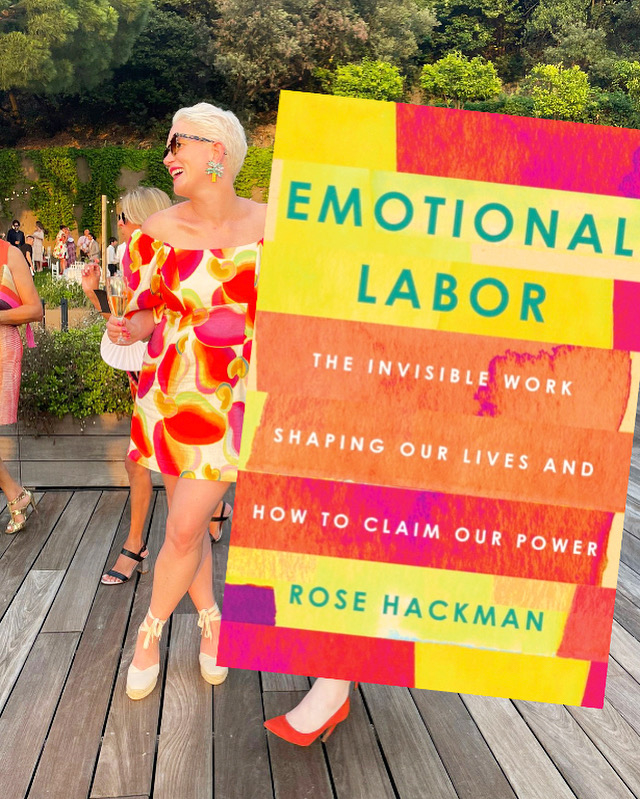 Rose, in a ruffled dress, stands next to a life-sized book cover of &quot;Emotional Labor&quot;