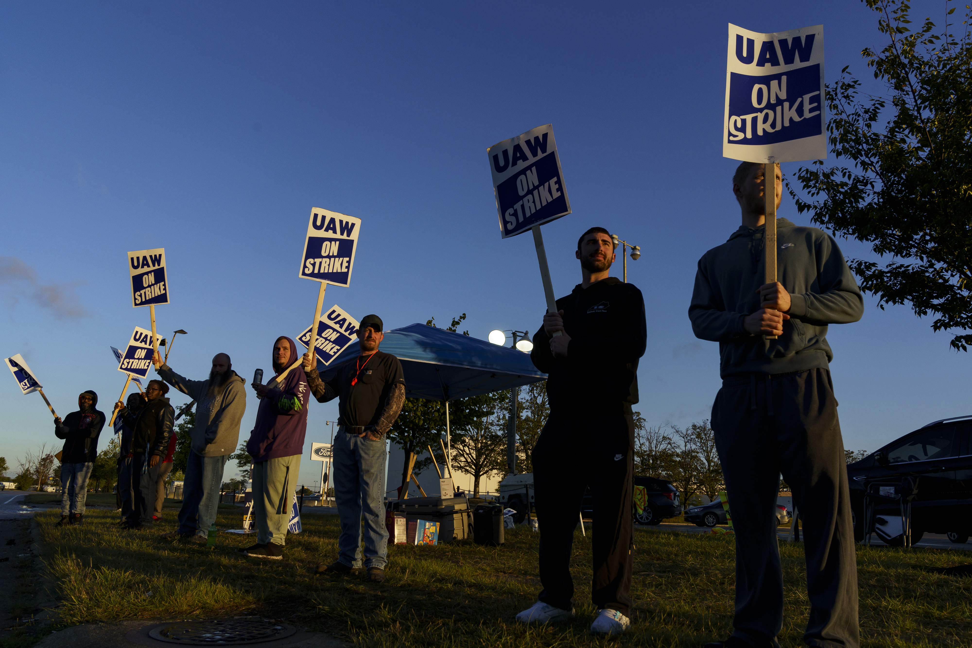 Group of people with UAW on Strike signs standing in a line during daylight