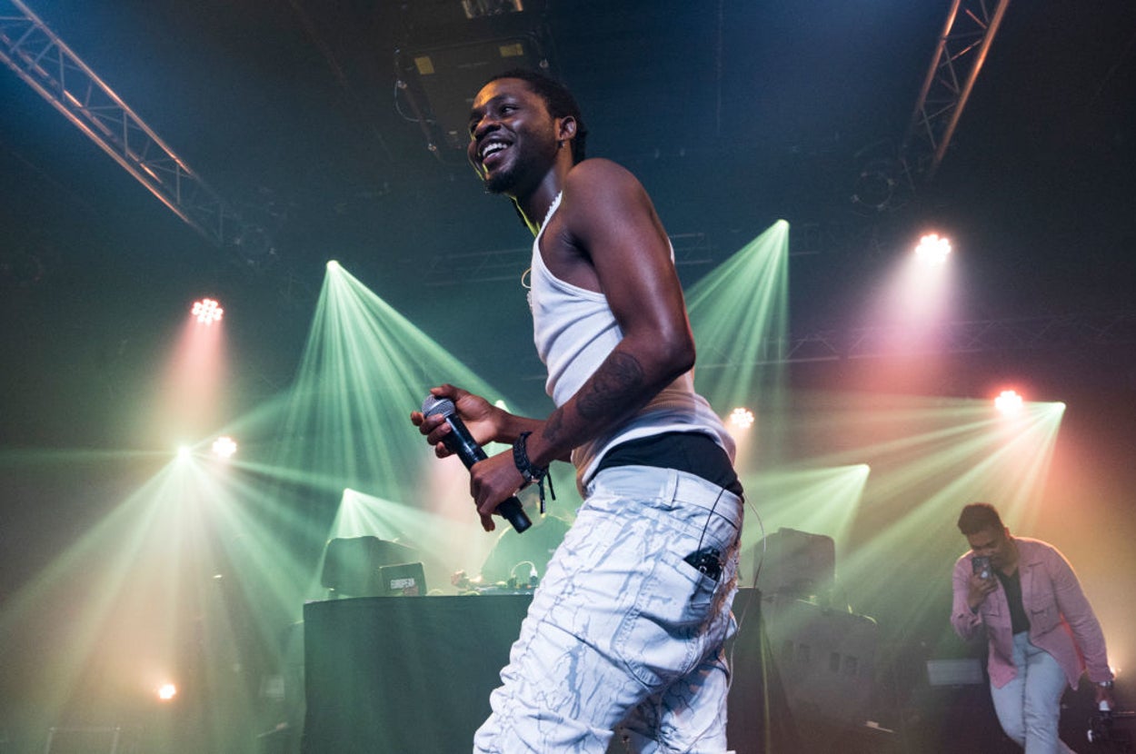 Music artist performing on stage with microphone and bright stage lights in the background