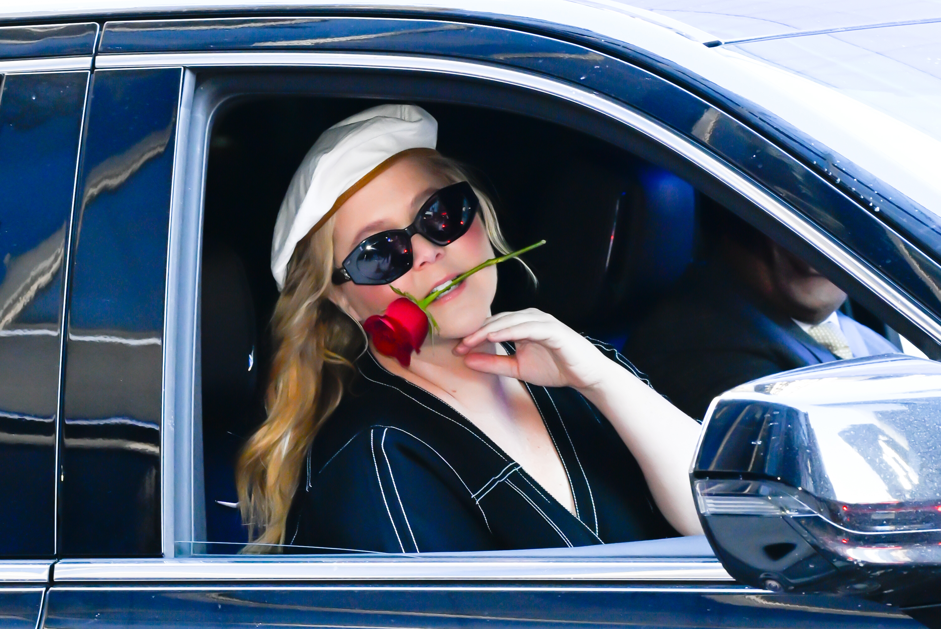 amy in the passenger seat with a rose in her mouth