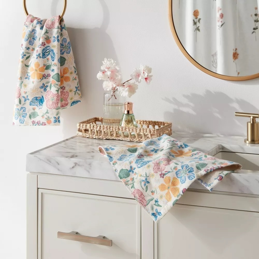 Floral-patterned towels hang and lay in a bathroom setting