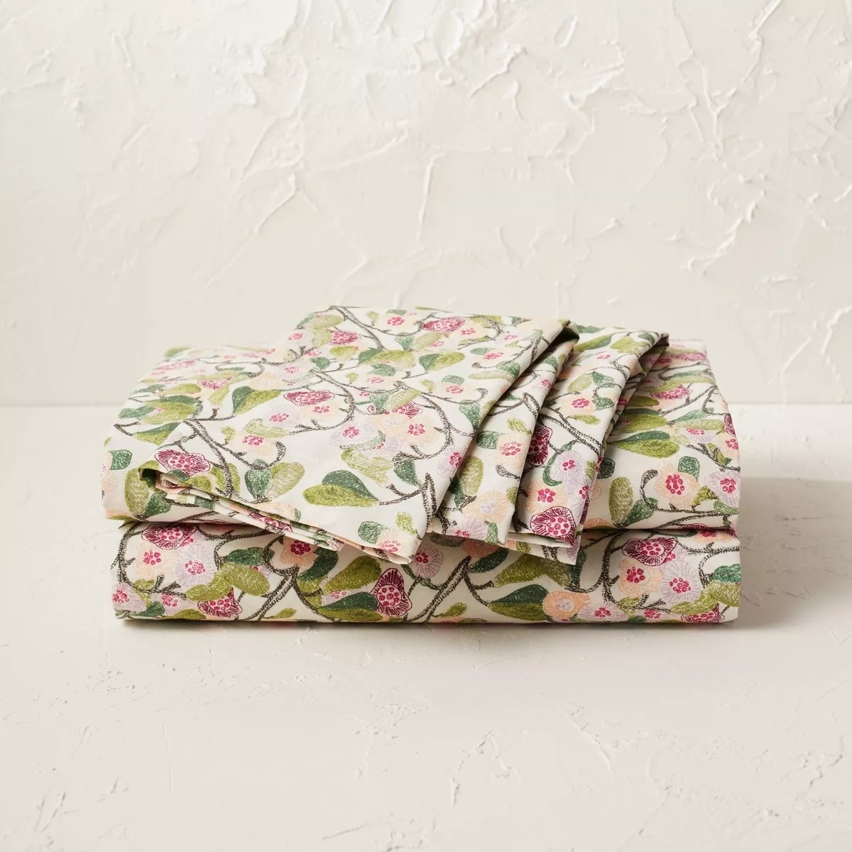 Floral patterned bedding set folded on a textured surface