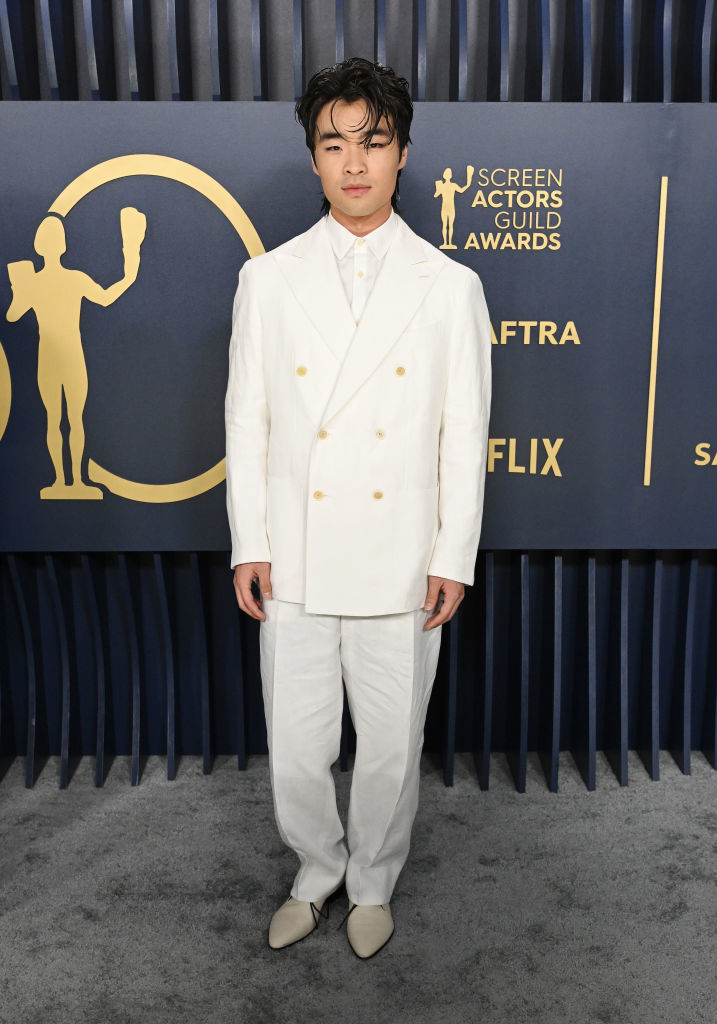 Dallas Liu in a double-breasted white suit with a non-traditional collar