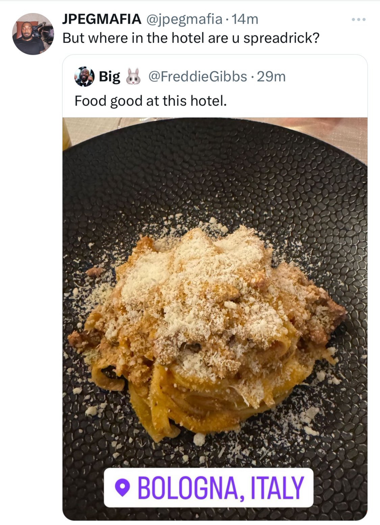 A dish of pasta with grated cheese on top, on a black plate, shown in a tweet conversation