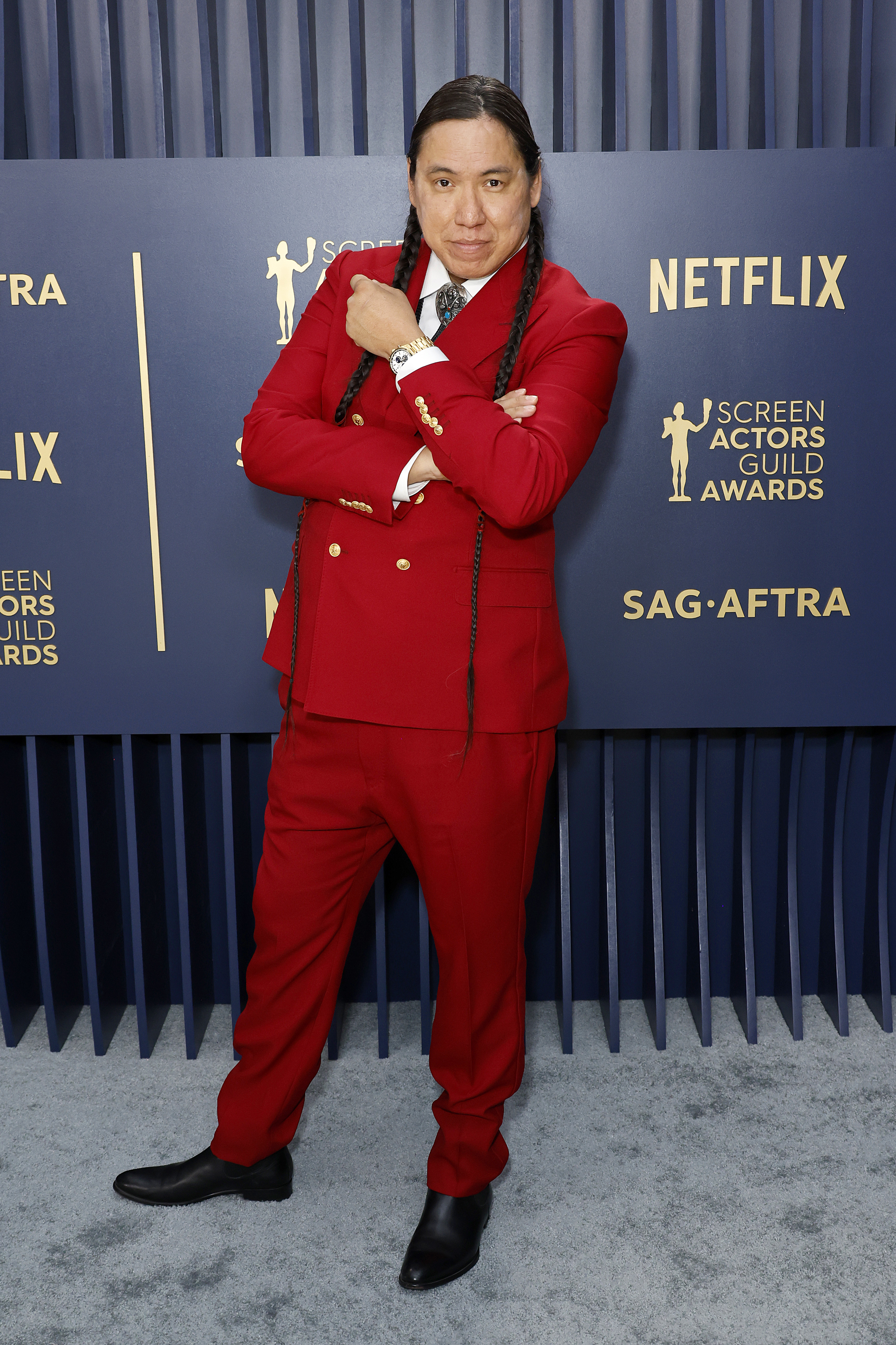 He&#x27;s wearing a red suit with long braided hair