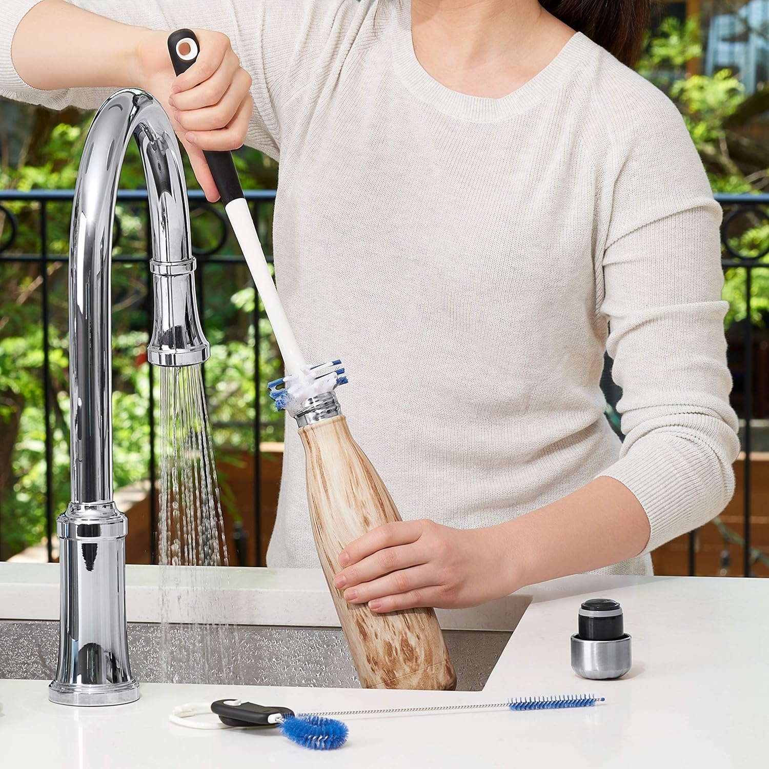 brush being used to scrub a water bottle in a sink