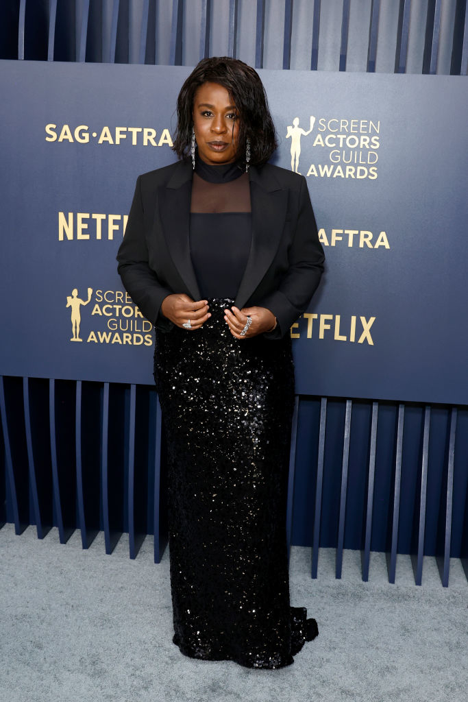Uzo Aduba posing in a black sequined skirt and sheer top with a cropped blazer