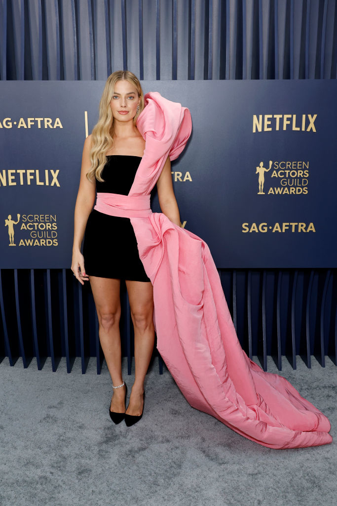 Margot Robbie in mini dress with large pink bow that goes down to the floor