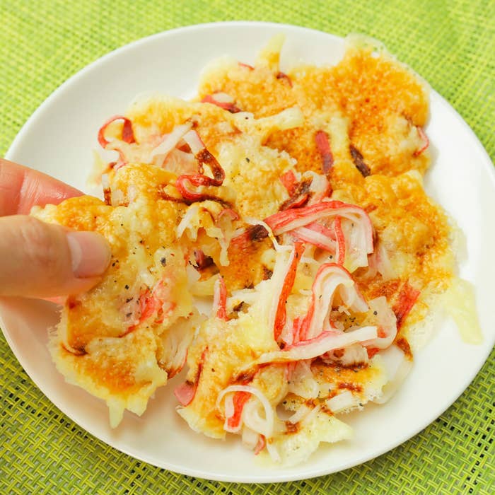 手で持っているカニカマとチーズのフリットが皿に盛られています。