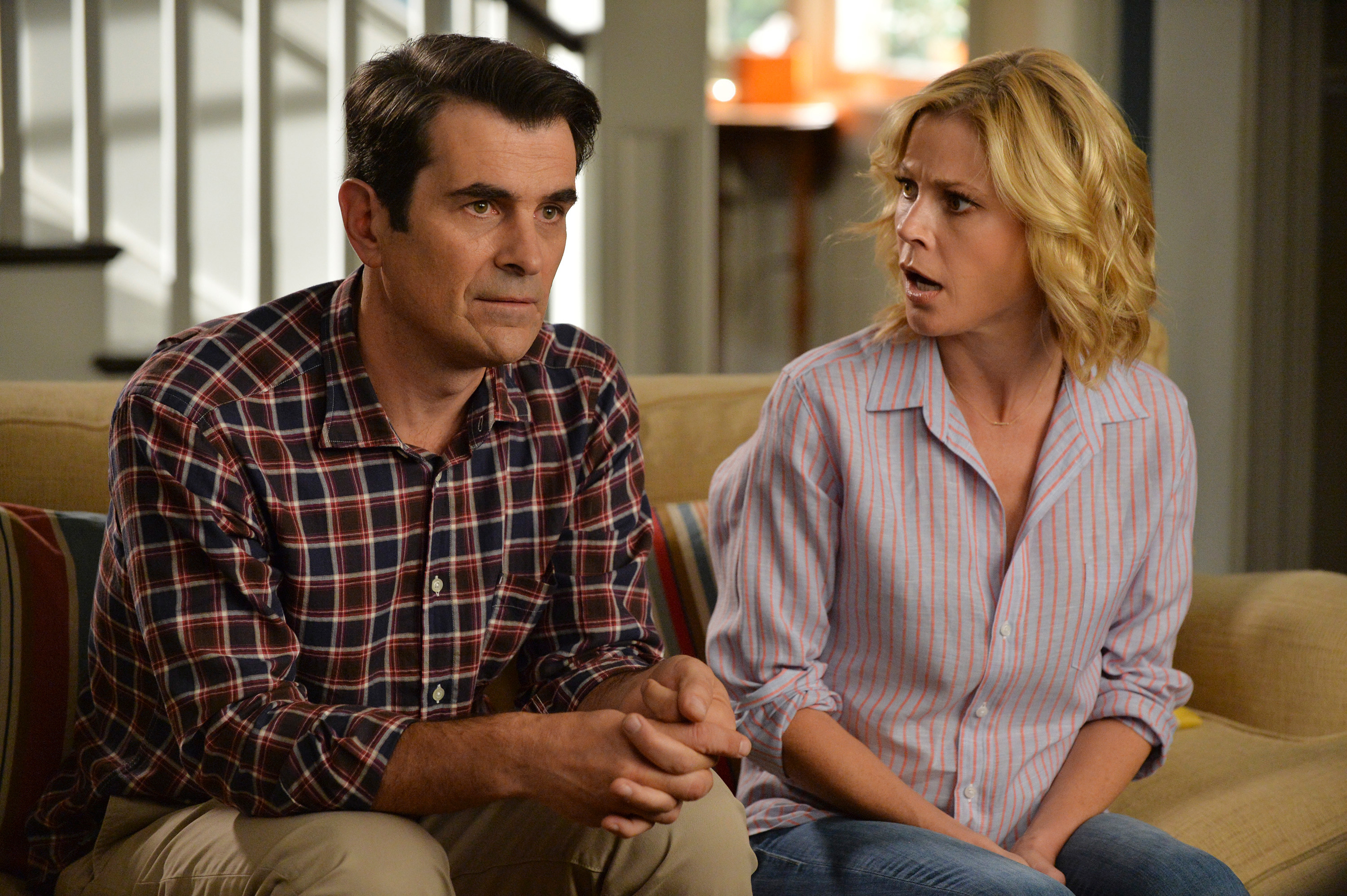 Ty Burrell and Julie Bowen, as Phil and Claire Dunphy, sit on a couch looking surprised in a scene from the TV show &#x27;Modern Family&#x27;