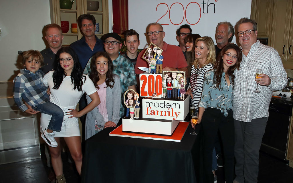 Cast of Modern Family celebrating 200th episode with a cake featuring show characters