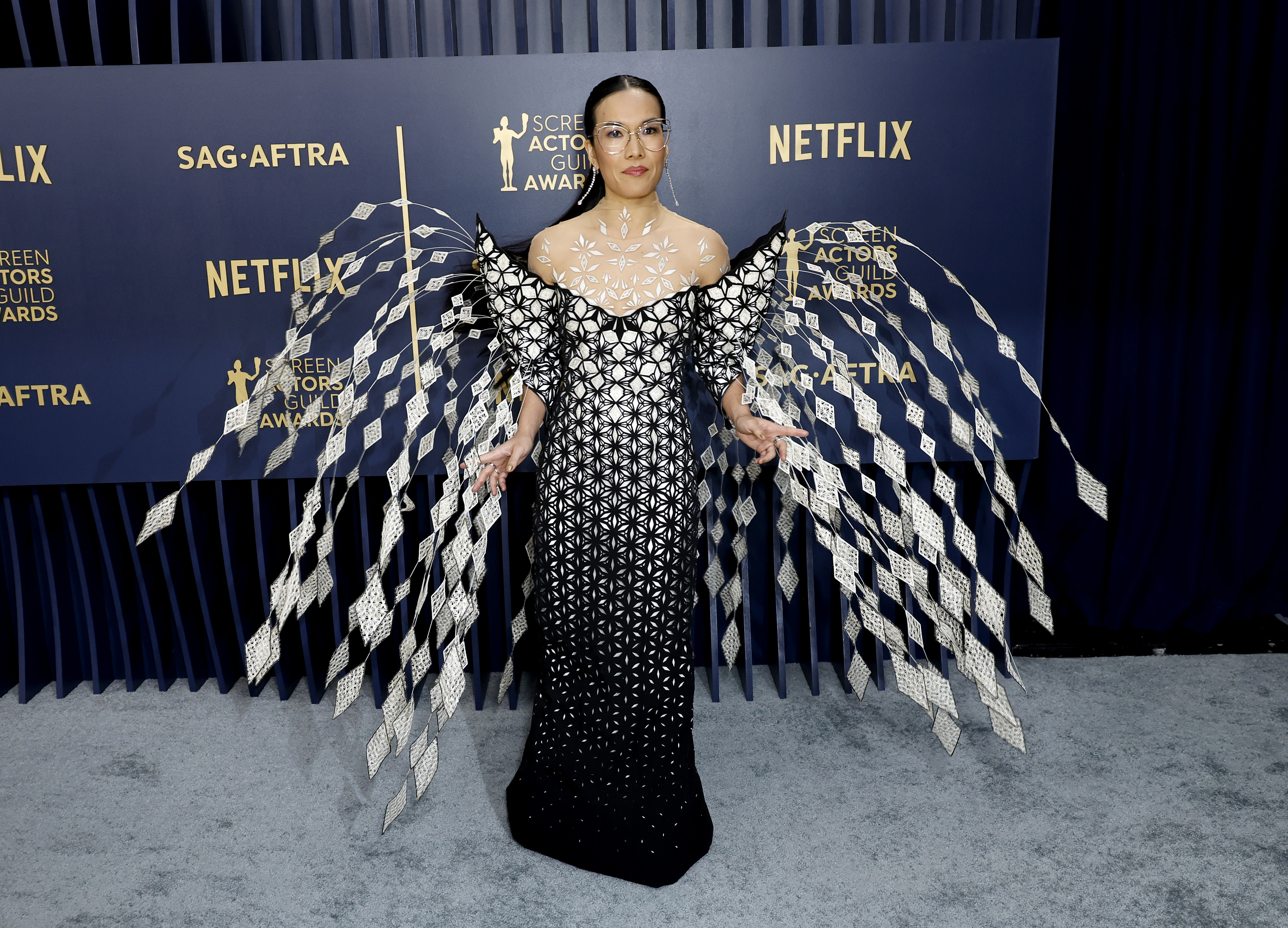 Ali Wong poses in a black-and-silver patterned dress with oversized winged sleeves