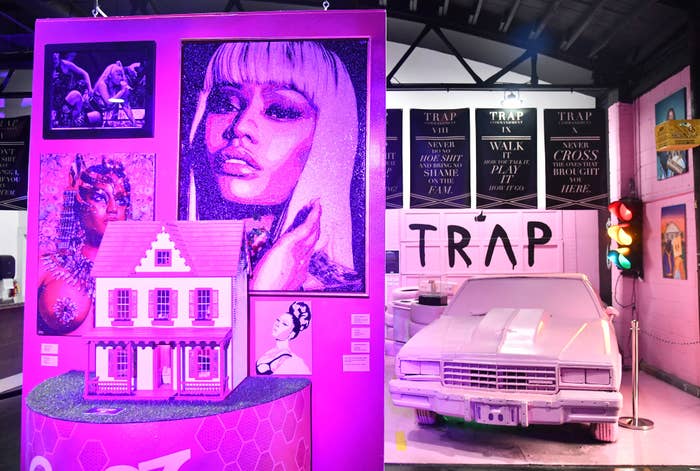 Exhibit displaying a pink house, car &amp; portraits with the word &quot;TRAP&quot; visible, part of a Nicki Minaj themed installation