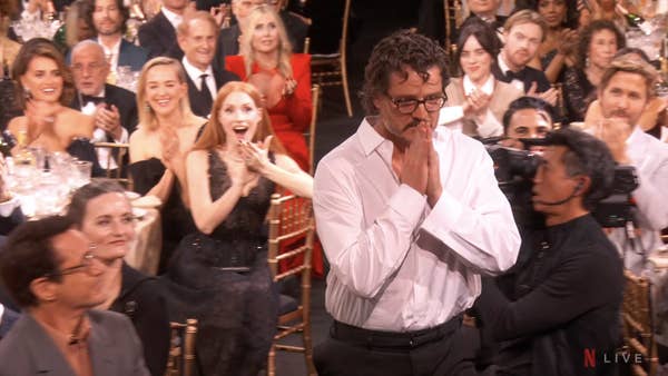 pedro clasping his hands and jessica in her seat behind him clapping with her mouth open in shock