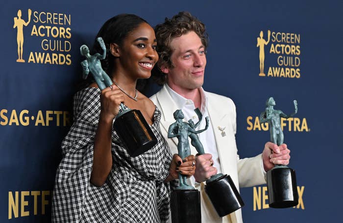 A closeup of ayo edebiri and jeremy allen white holding their awards