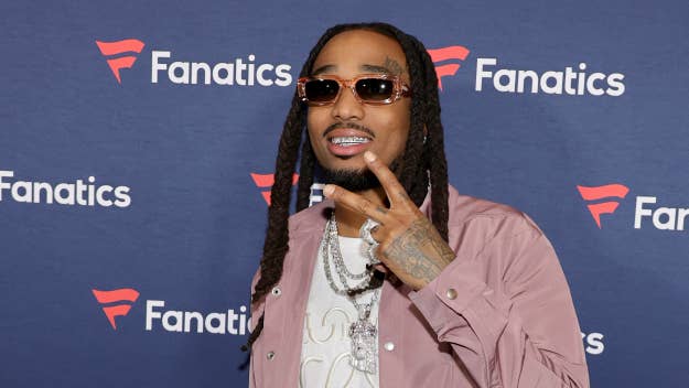 Quavo in a satin shirt flashing a peace sign at the Fanatics event