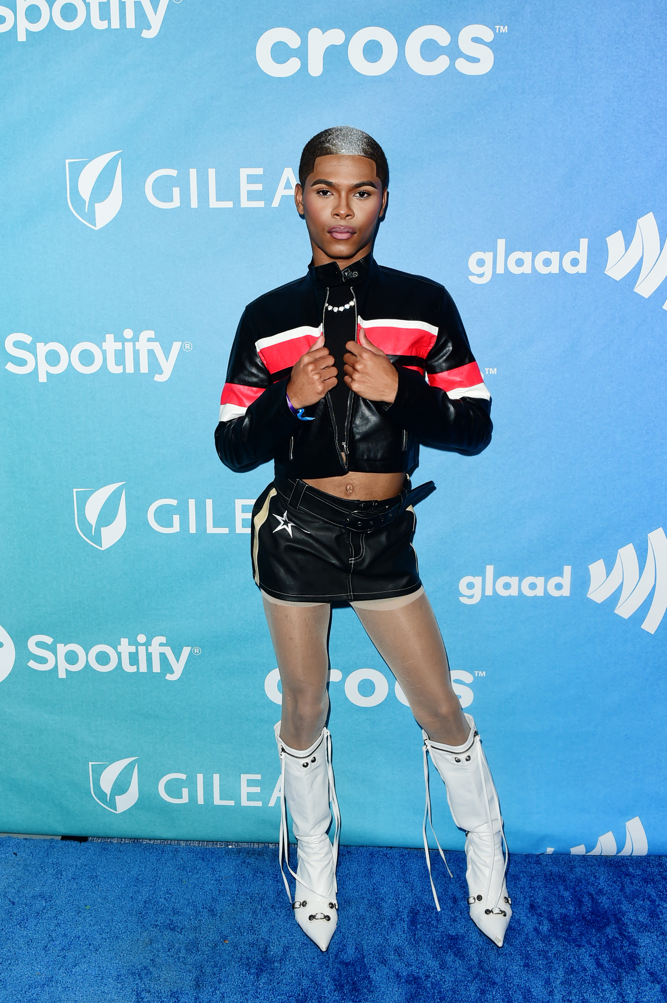 Kidd Kenn in a crop jacket, shorts with a star-detail, and knee-high boots posing at an event