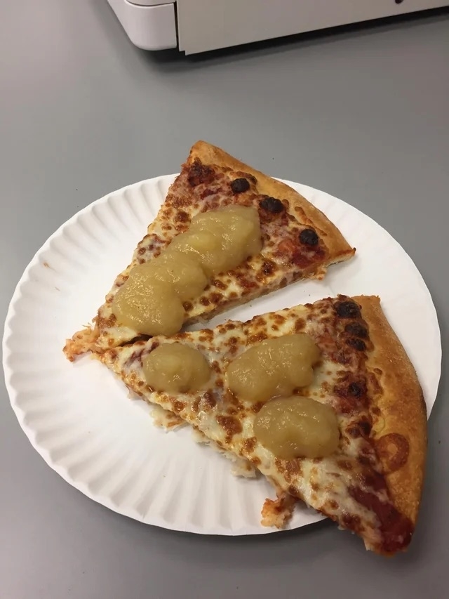 Two slices of pizza with topped with applesauce on a white plate