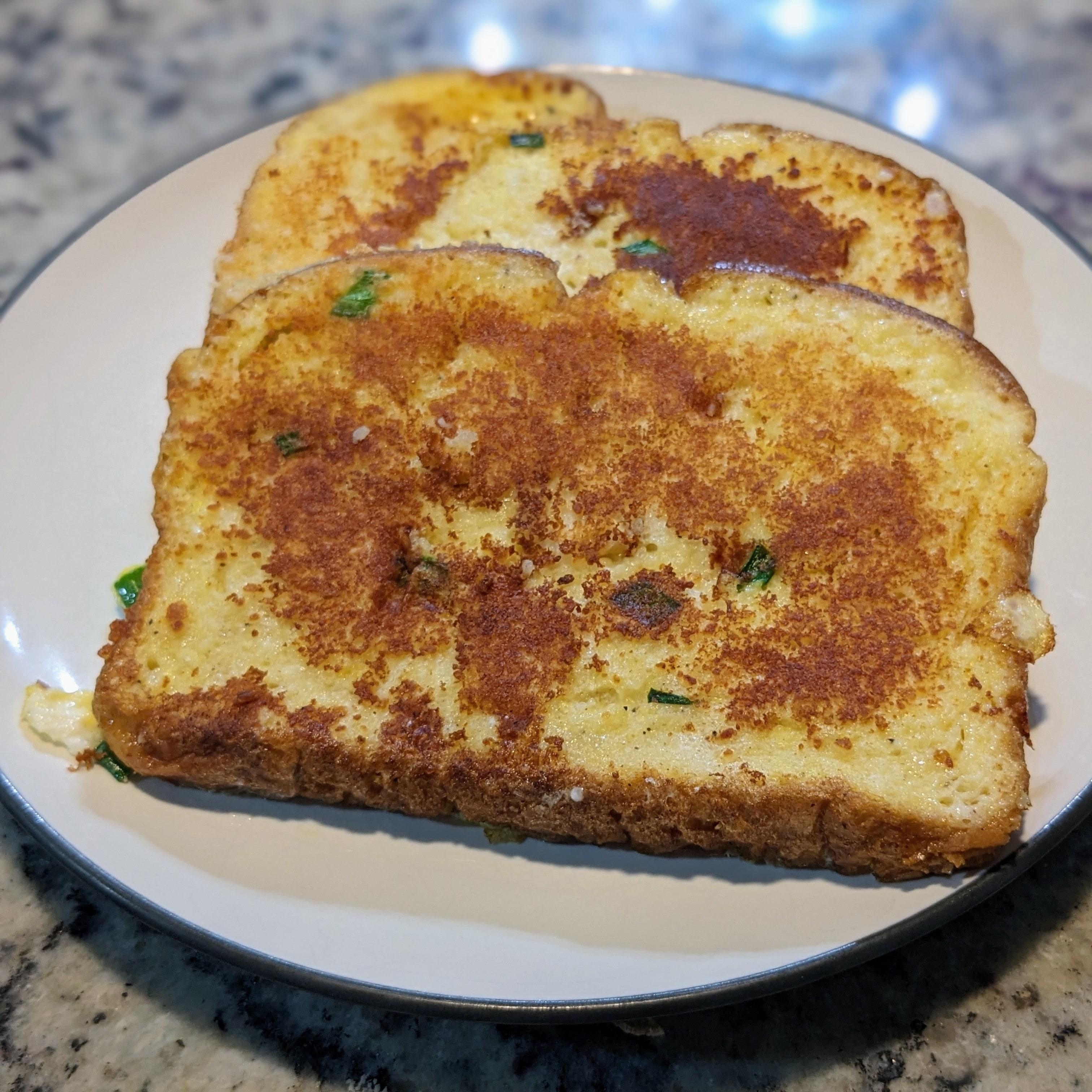 A plate with a single slice of grilled bread with herbs
