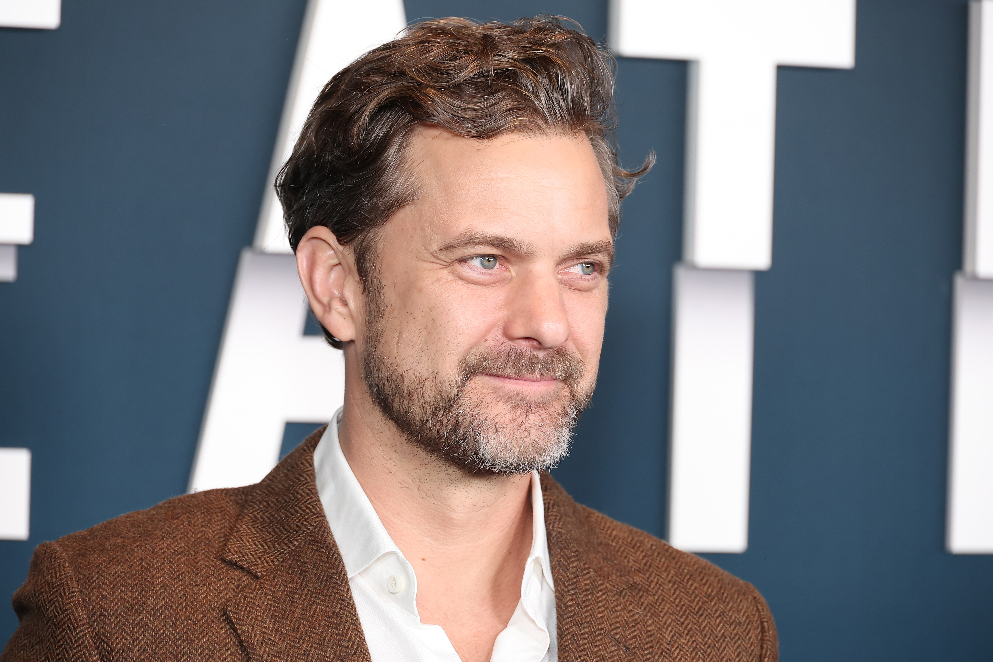Joshua Jackson in a blazer and shirt, smiling at an event