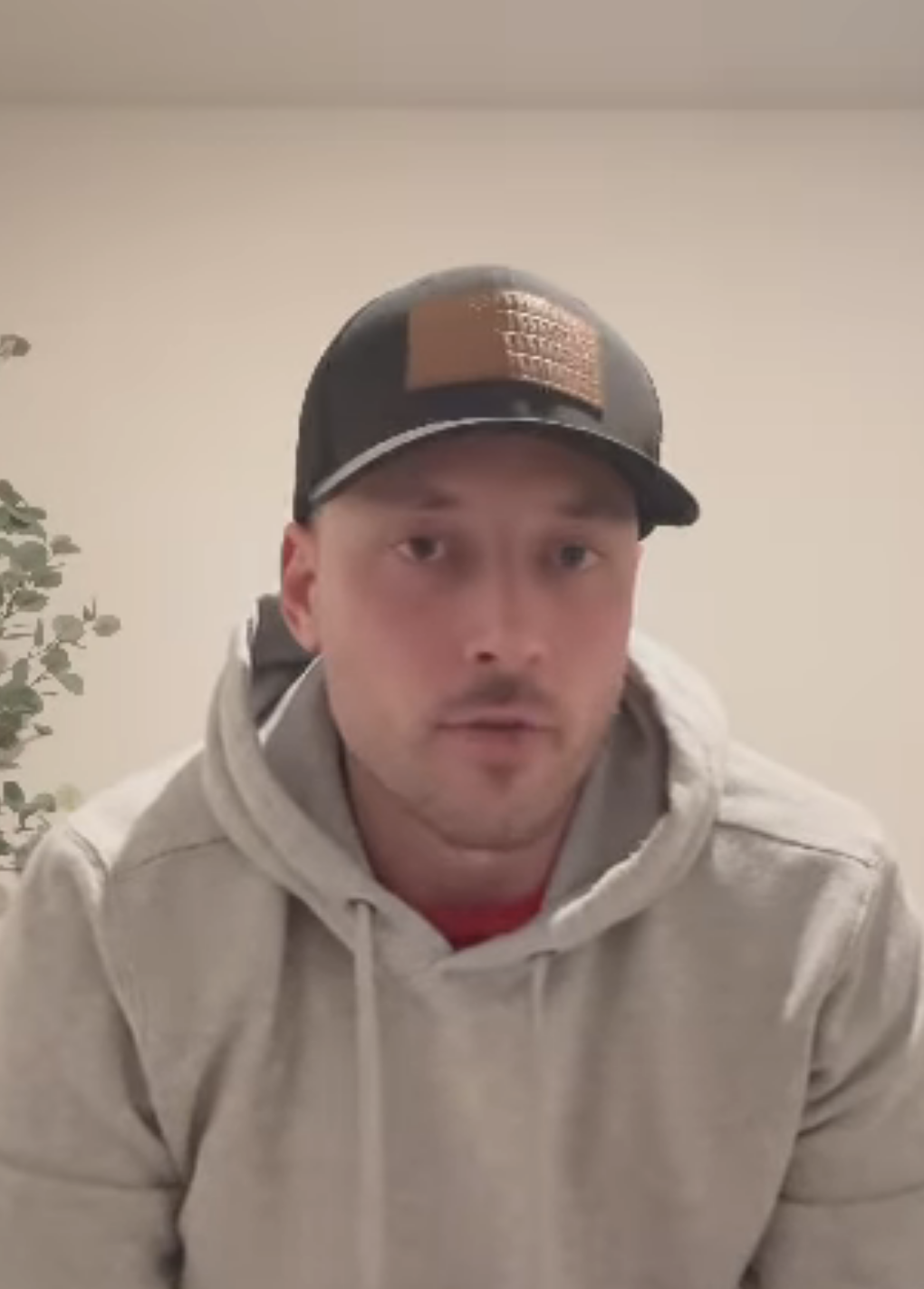 Man in a cap and hoodie speaking in a video, potentially for an online audience or interview