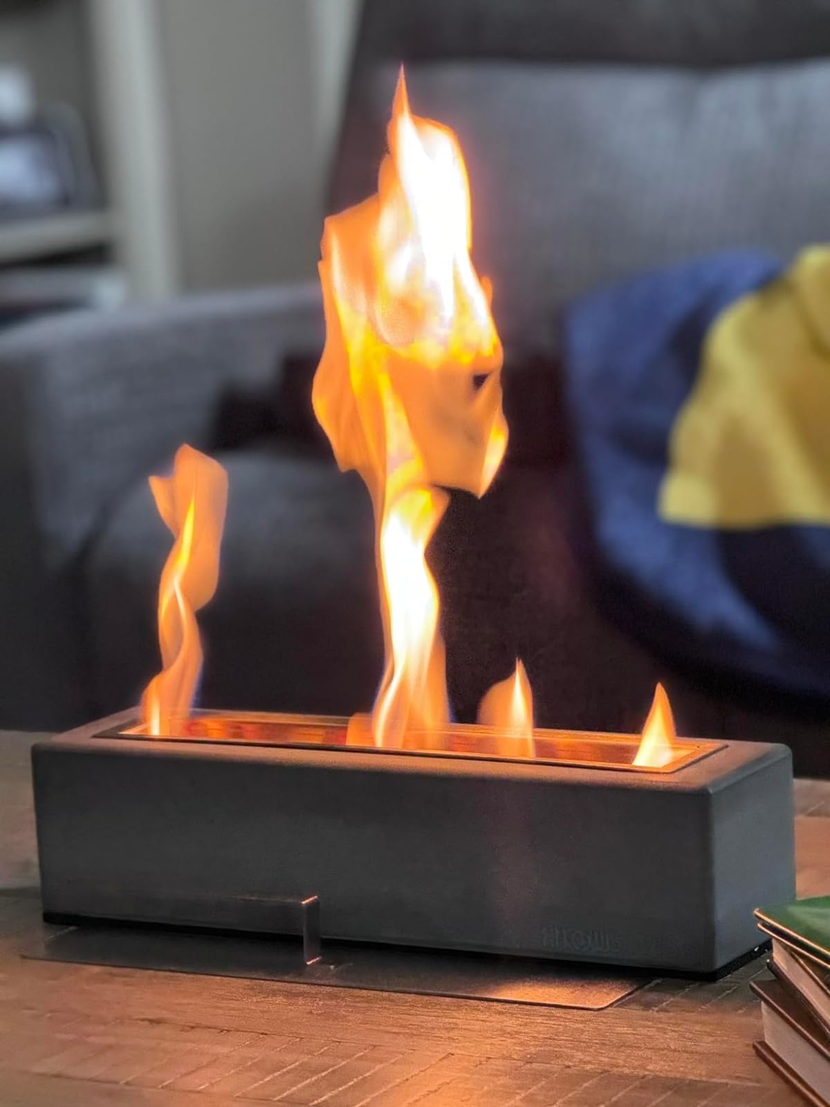 Portable tabletop fireplace with visible flames on a wooden surface, indoors