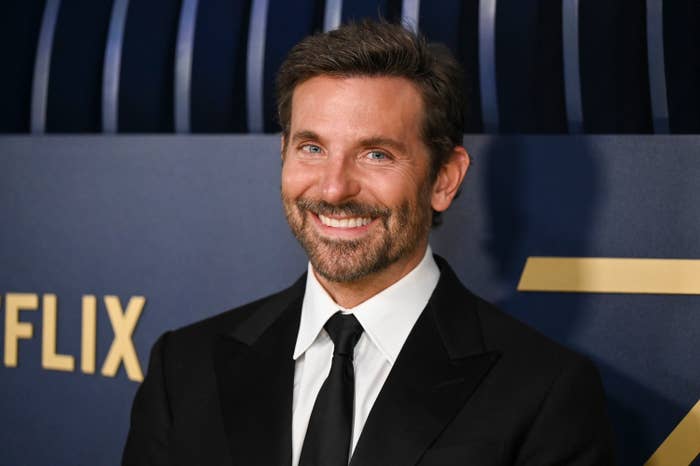Bradley Cooper smiling while wearing a suit at a Netflix event