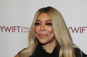 Wendy Williams stands posing in a black sleeveless dress with a belt at an event