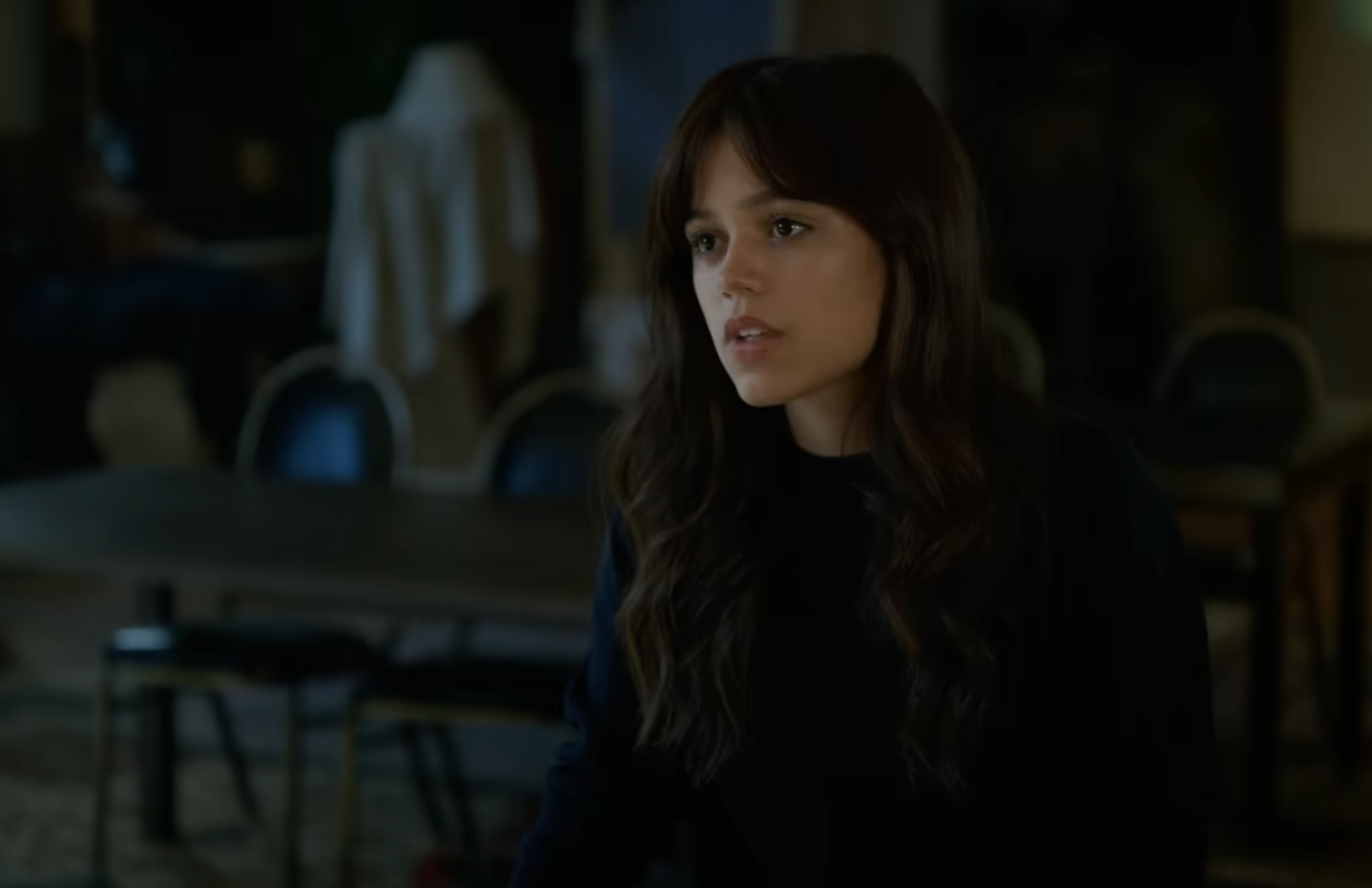 Jenna wearing a sweater, sitting, looks concerned in a scene from the film
