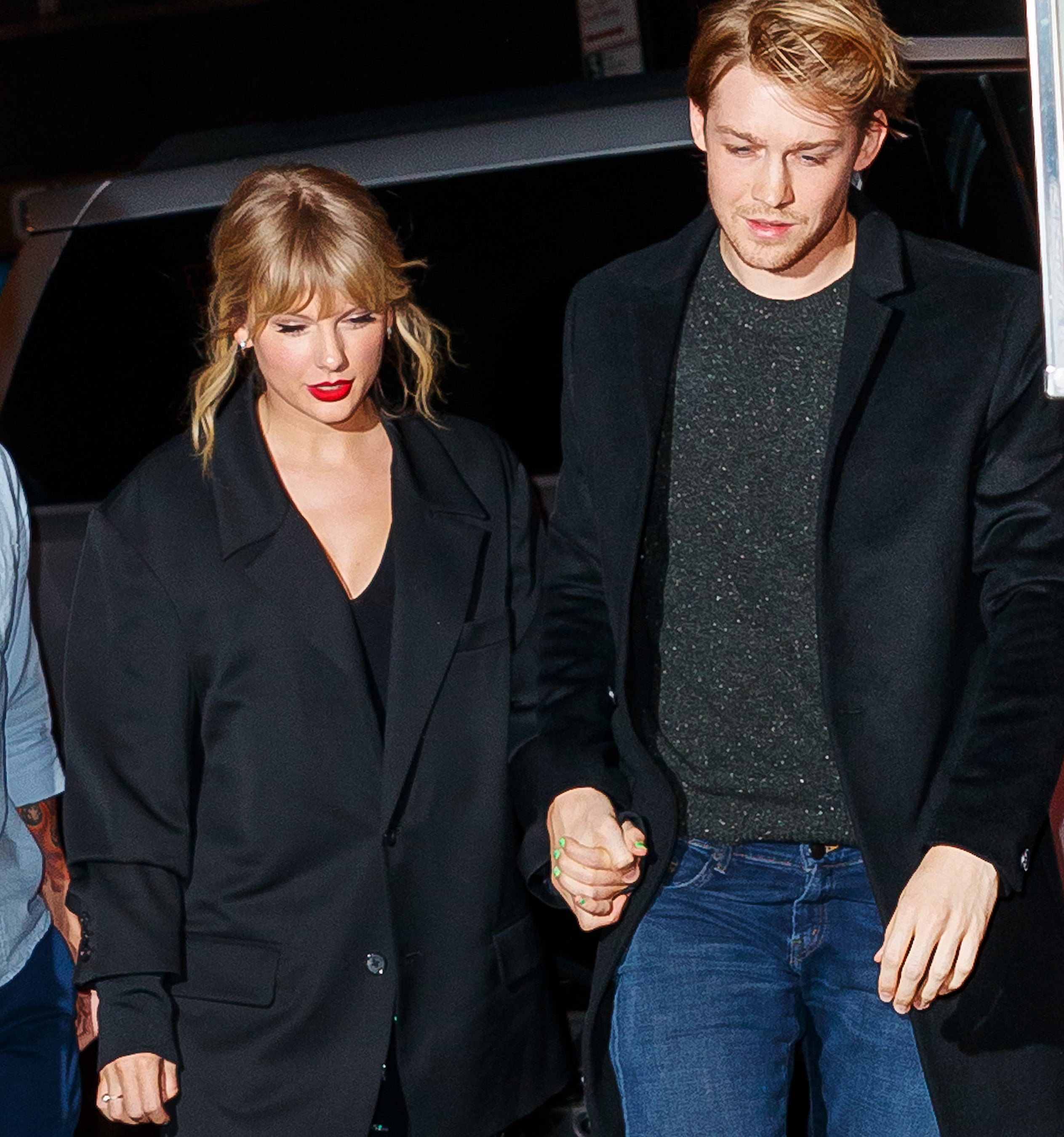 Taylor Swift with Joe Alwyn, both in stylish dark coats, walking and holding hands