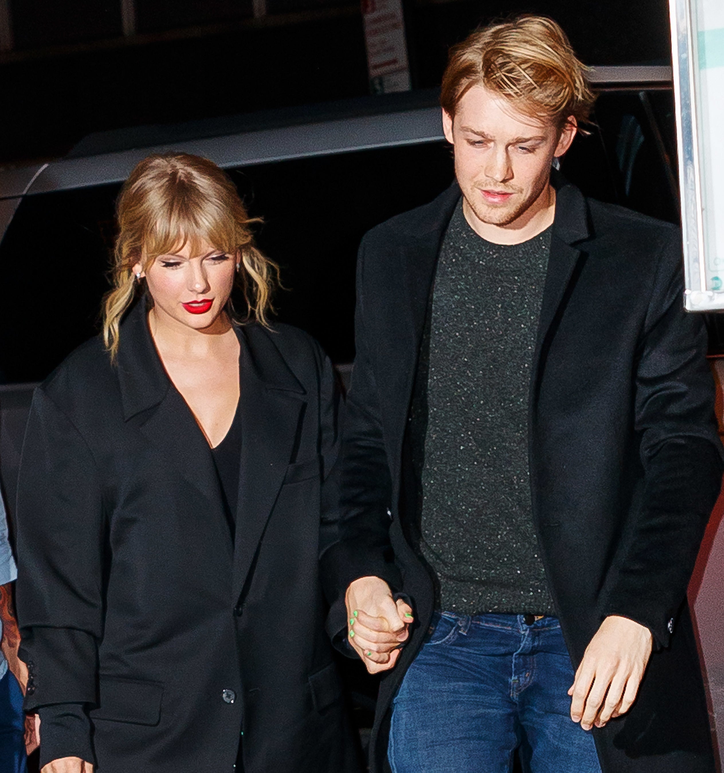 Taylor Swift with Joe Alwyn, both in stylish dark coats, walking and holding hands