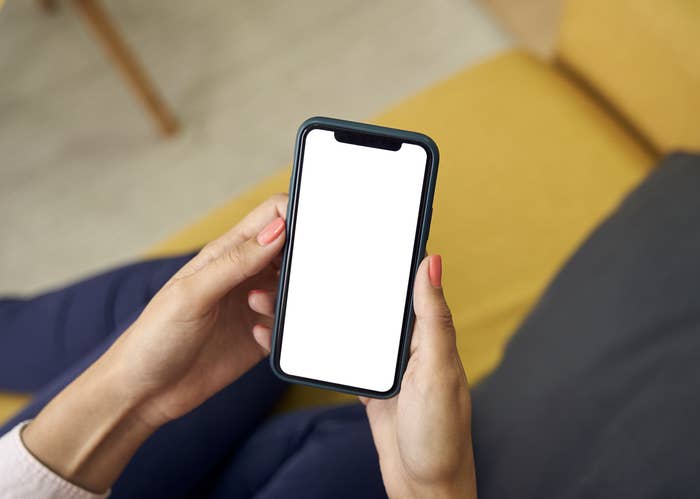 Person holding a smartphone with a blank screen
