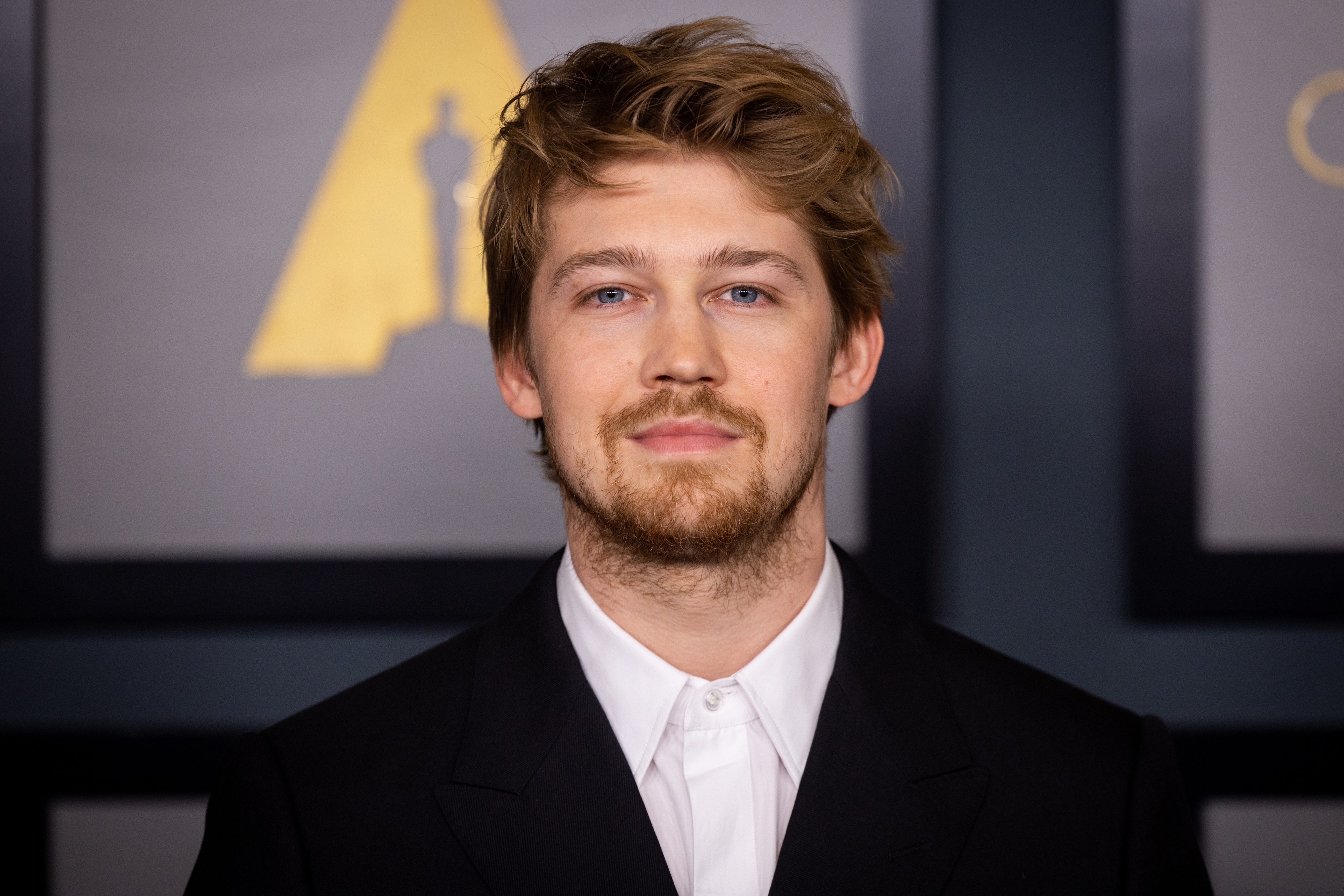 Joe Alwyn in a suit posing for a photo at a media event