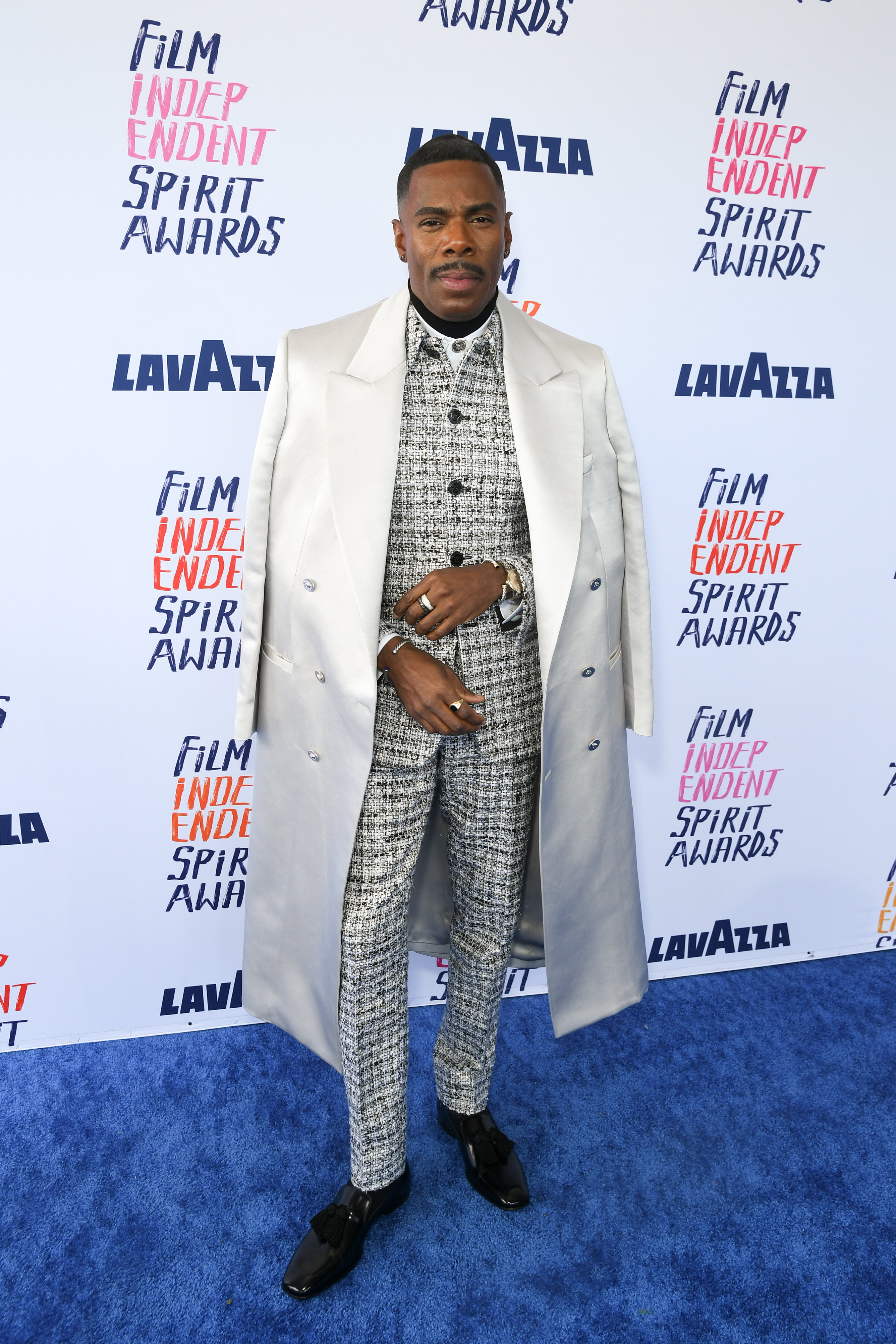 Colman in a patterned suit with overcoat posing at Film Independent Spirit Awards