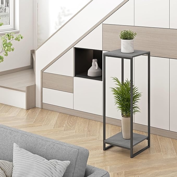 A modern room with a minimalist plant stand holding two potted plants by a stairway