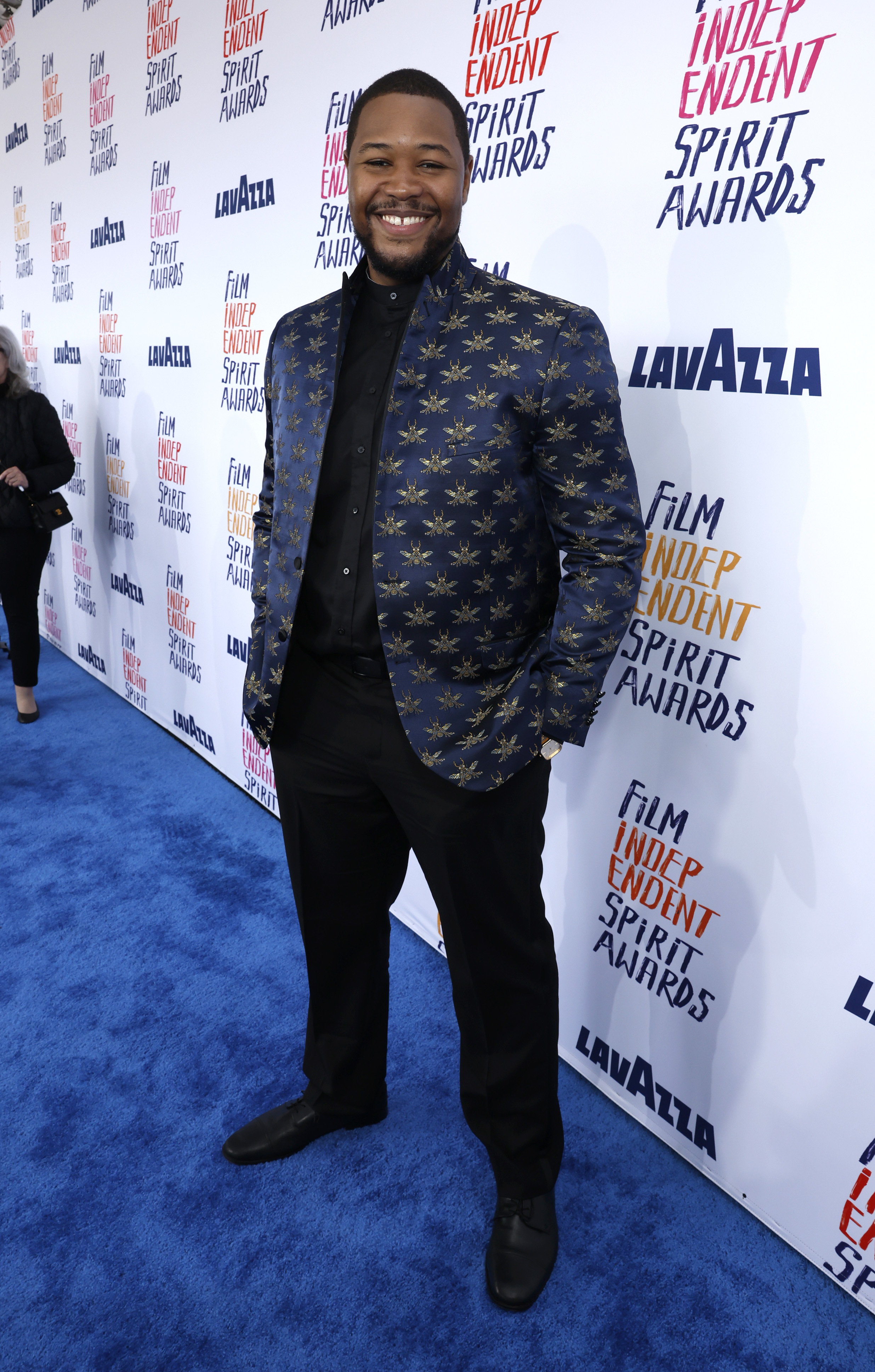 Luke Tennie in patterned jacket and trousers poses at the Film Independent Spirit Awards