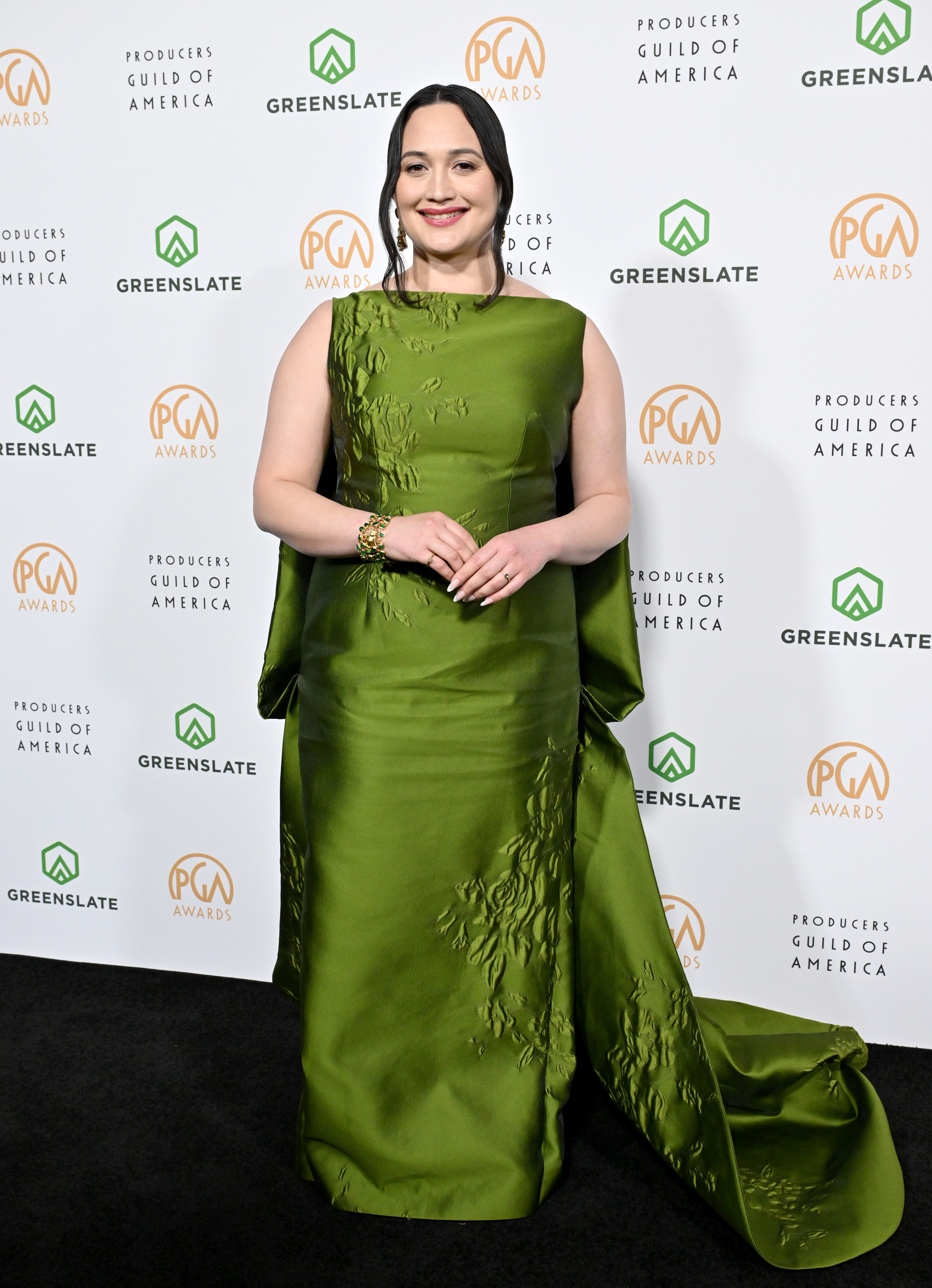 Lily in an elegant gown with leaf-like textures poses on the Producers Guild Awards red carpet