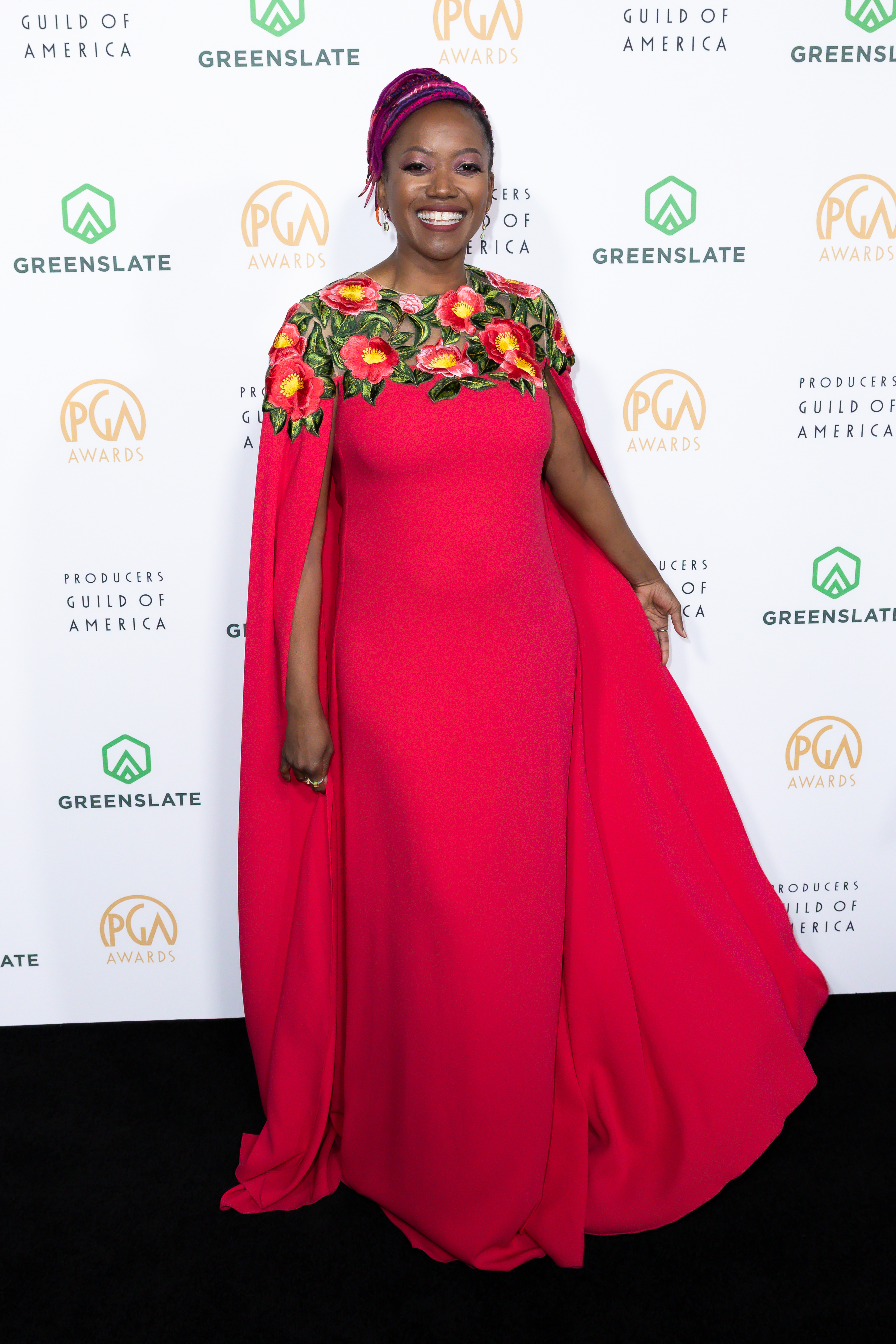 Erika Alexander in a cape-style gown with floral embellishments smiling