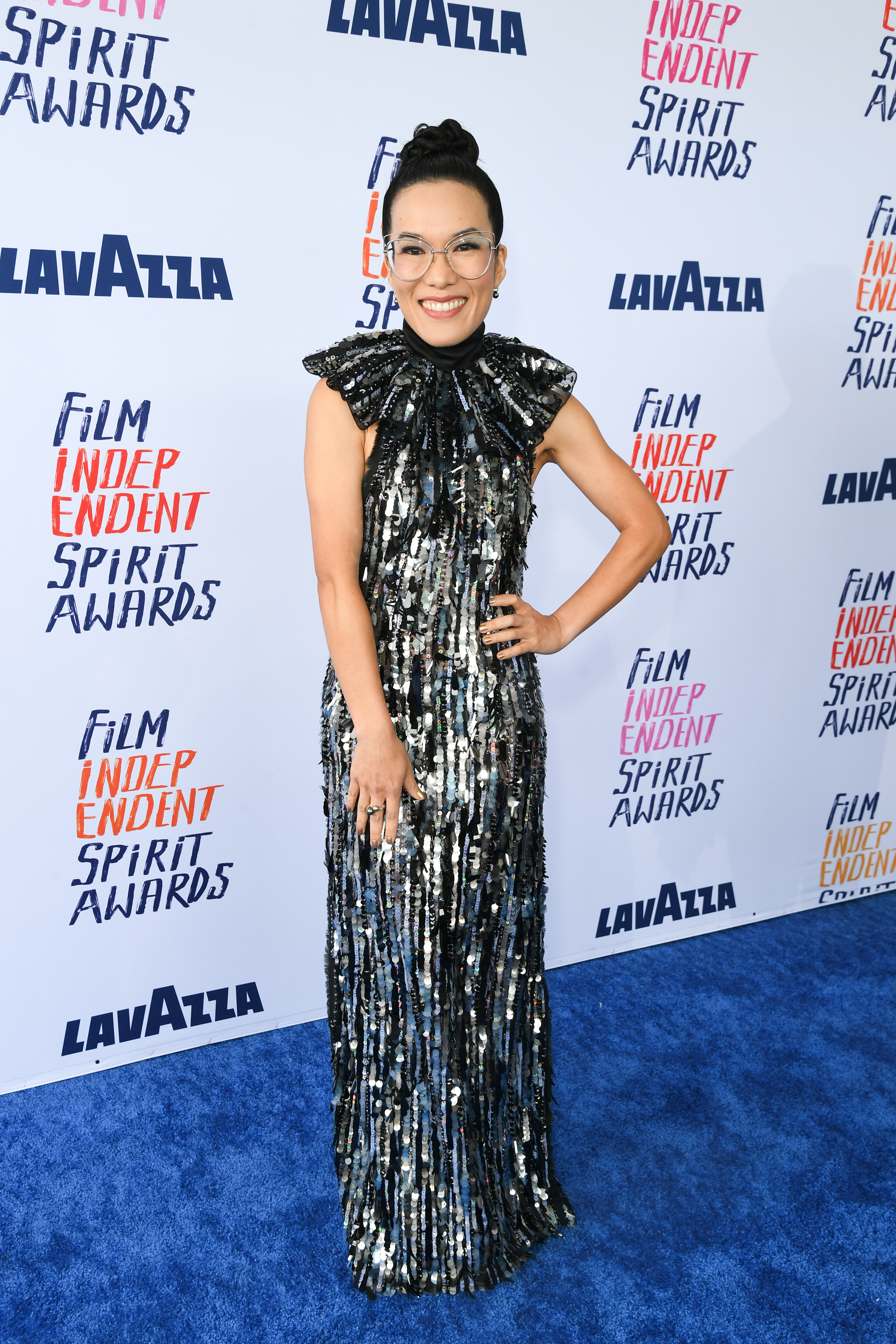 Ali posing in a sequined gown with a high neck and ruffled details