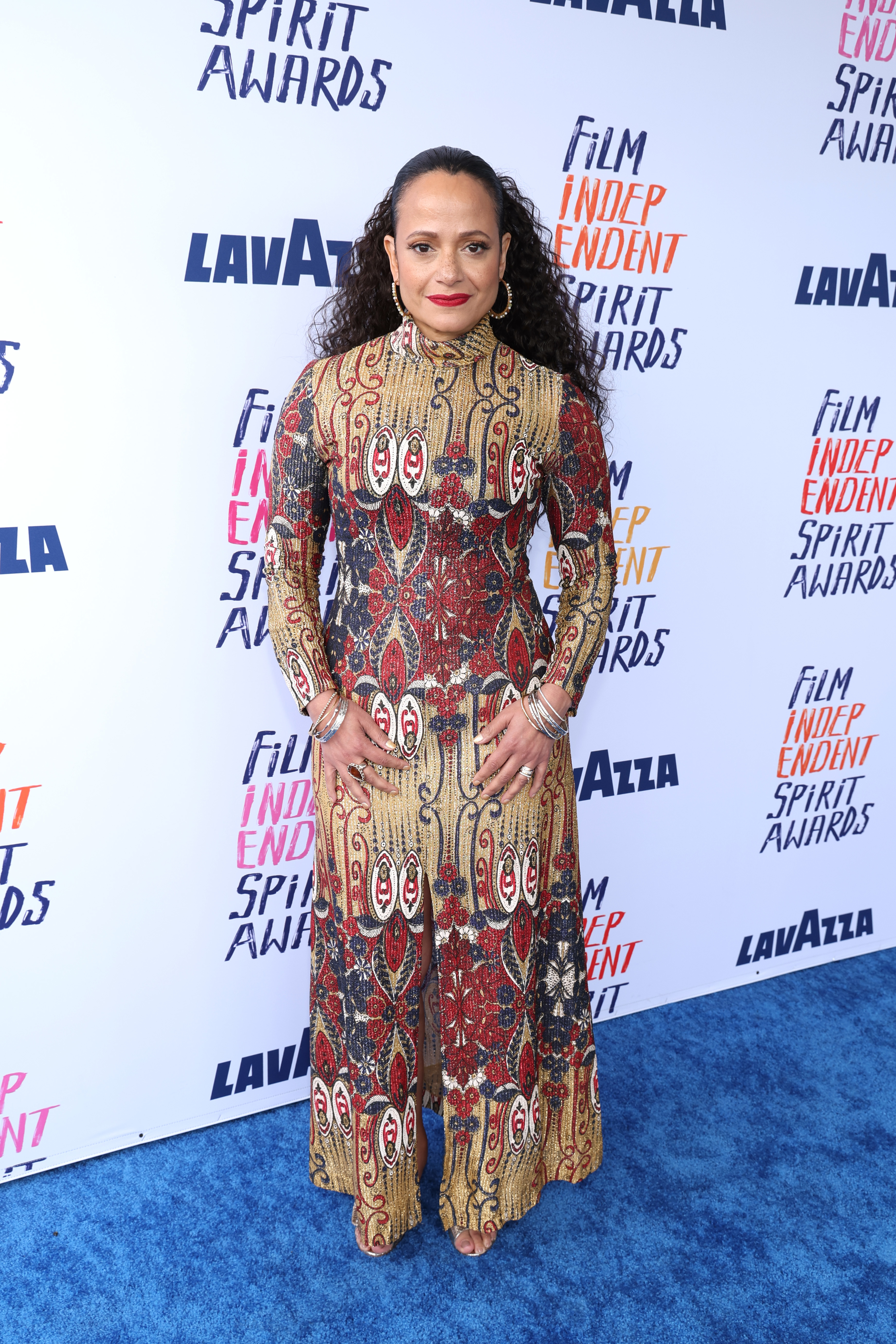 Judy Reyes in patterned long-sleeve gown standing at the Film Independent Spirit Awards