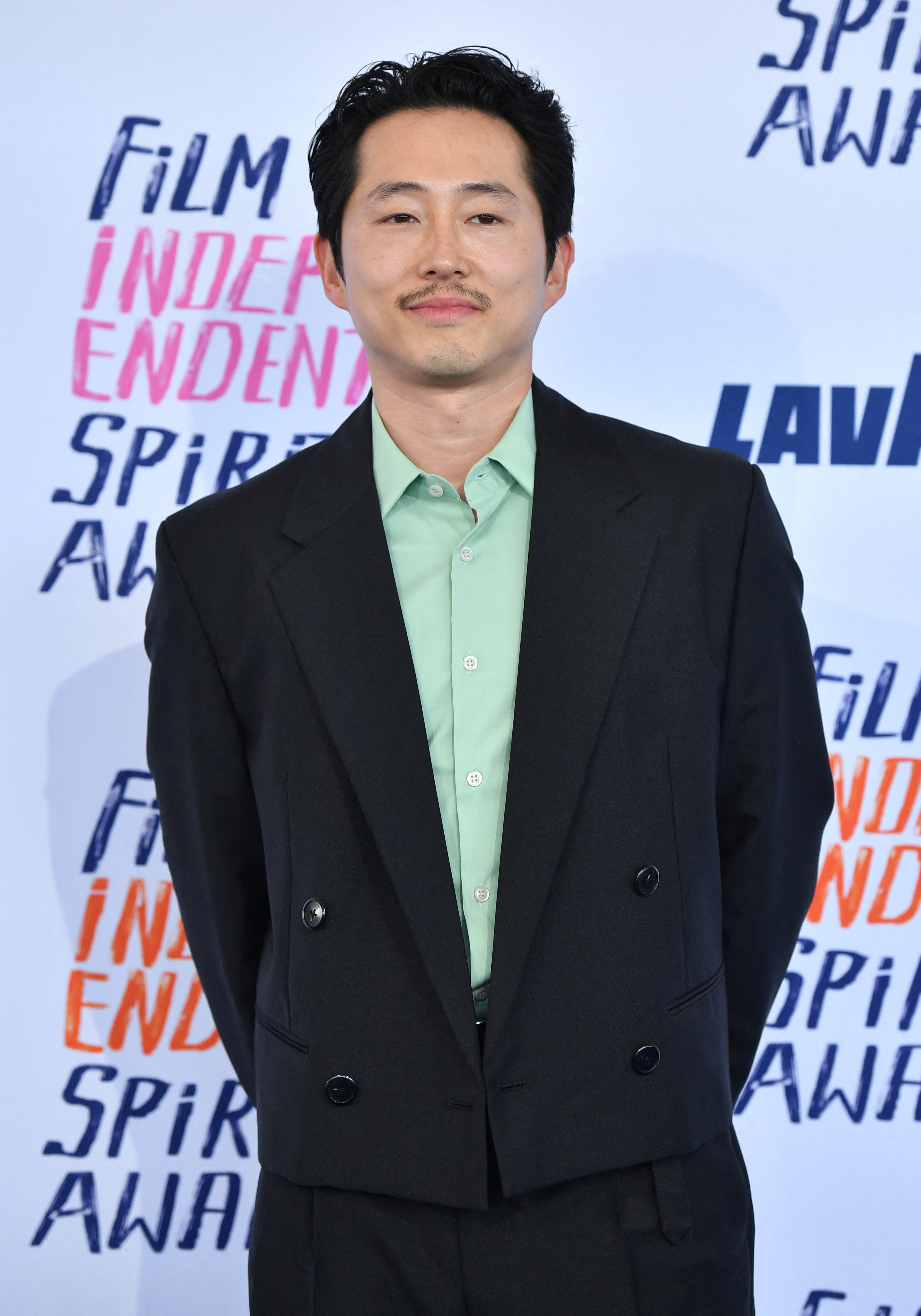 Steven Yeun in a suit and mint shirt at the Spirit Awards