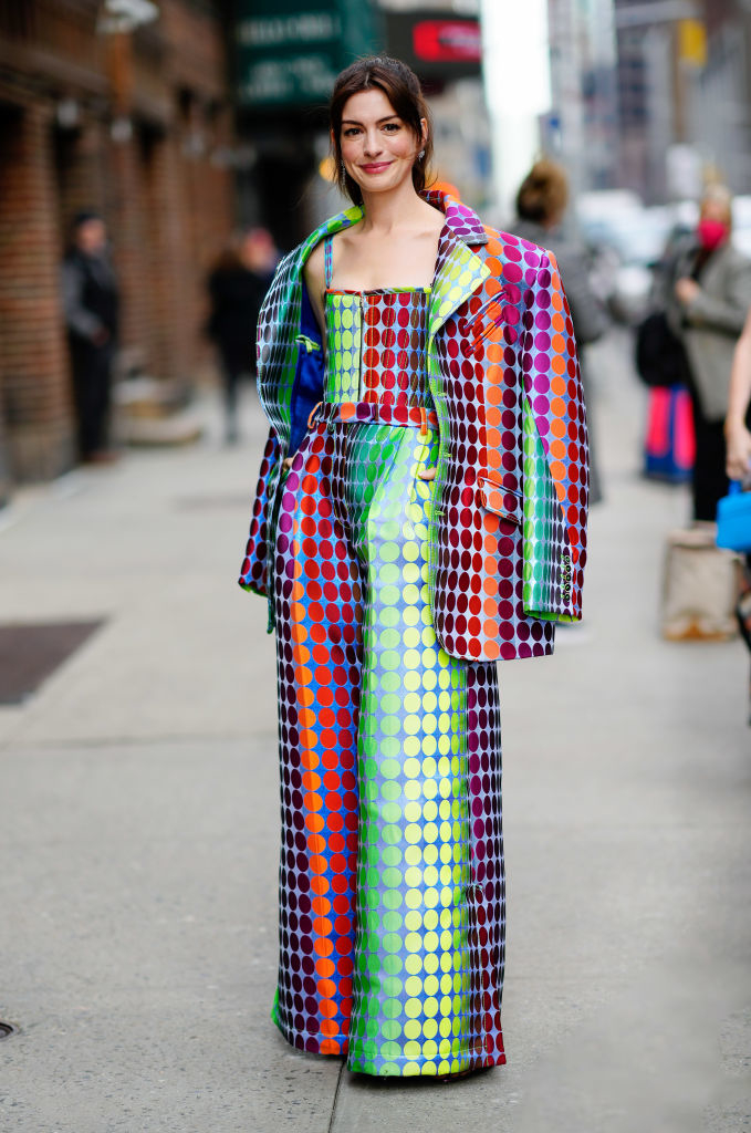 Annd in vibrant polka-dot print gown with oversize matching coat on city street