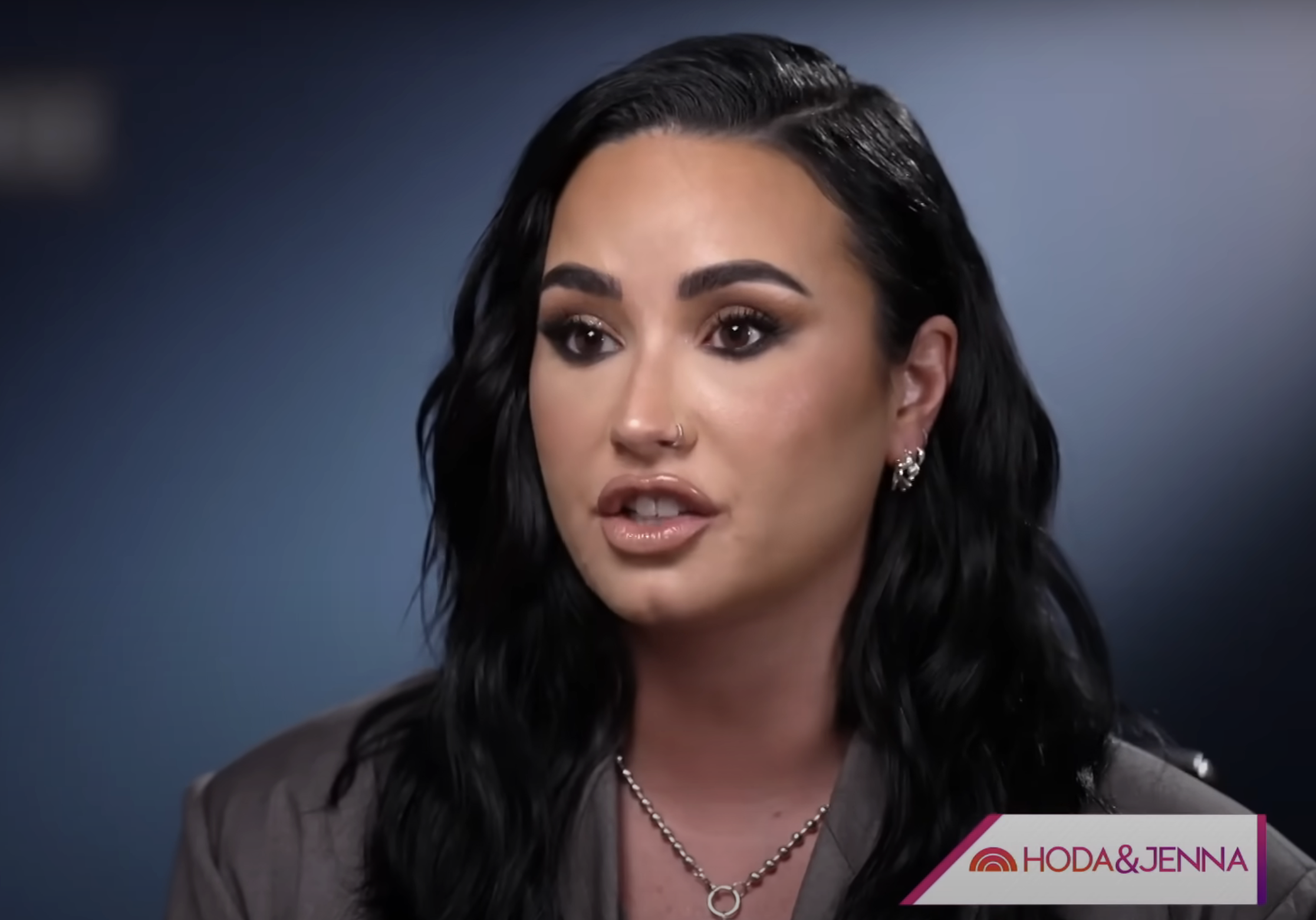 Demi Lovato in a close-up interview, wearing a structured top and silver chain necklace