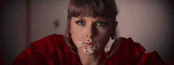 Taylor Swift with frosting on her face, wearing a red top, looking surprised