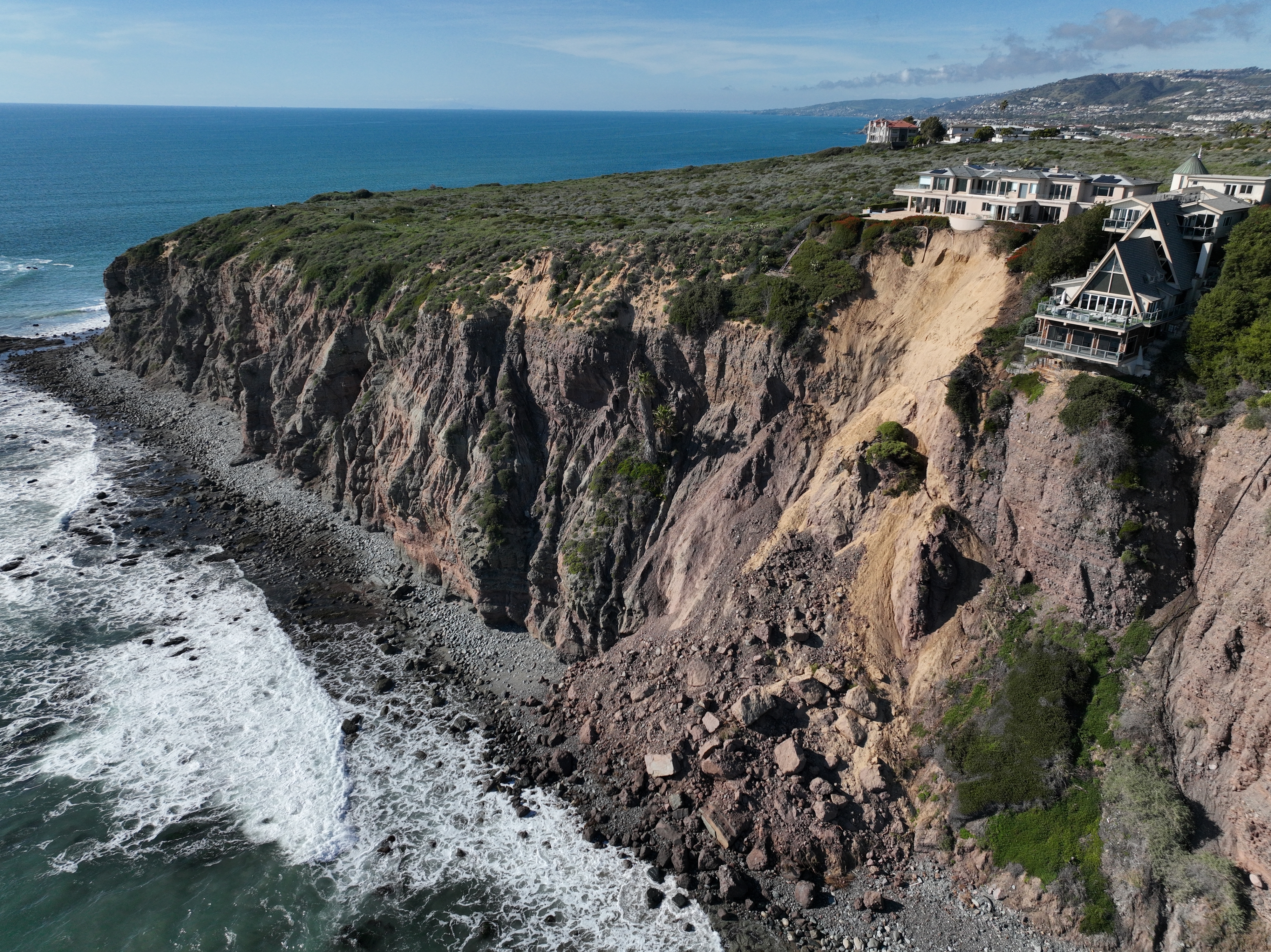 Coastal cliffside with houses perched on the edge overlooking the ocean waves below
