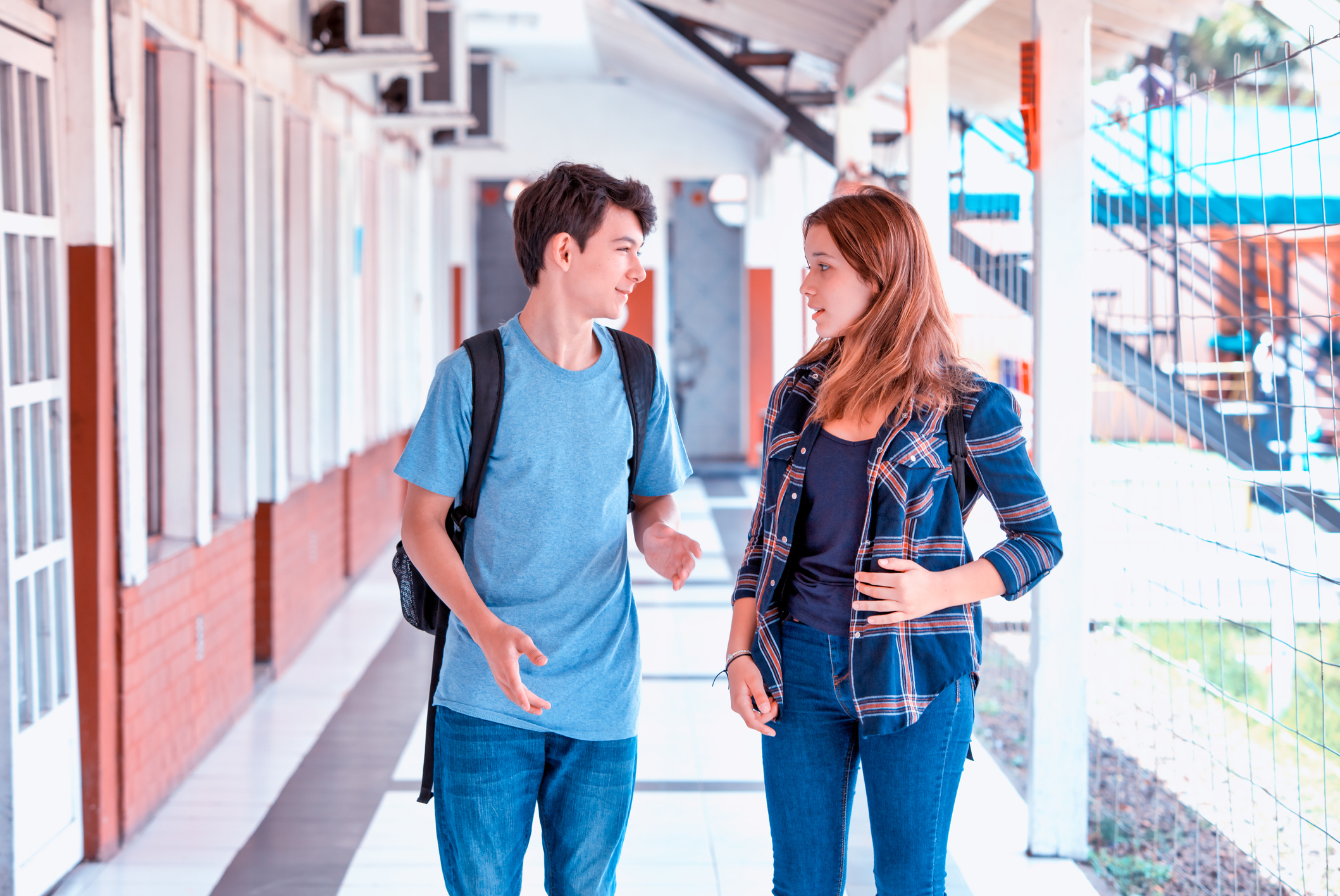 Two people chatting while walking in a school hallway