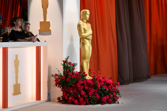 Oscar statue beside red roses, with people in the background at an award event