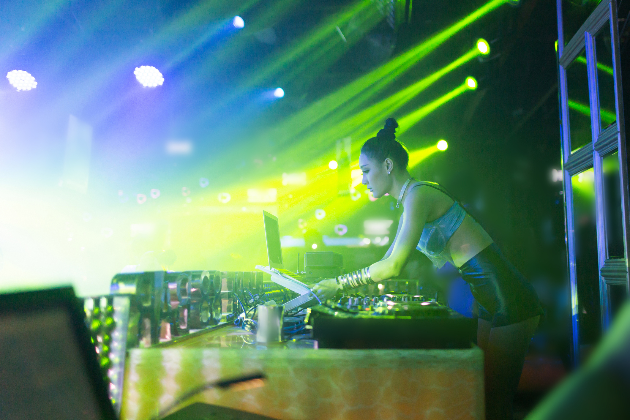 Woman DJing at a club with vibrant lights in the background